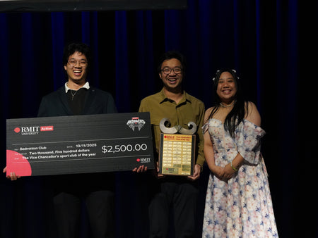 Three RMIT Active Awards Night winners on stage holding an oversized $2,500 cheque for the Badminton Club and the Vice-Chancellor's Sport Club of the Year plaque