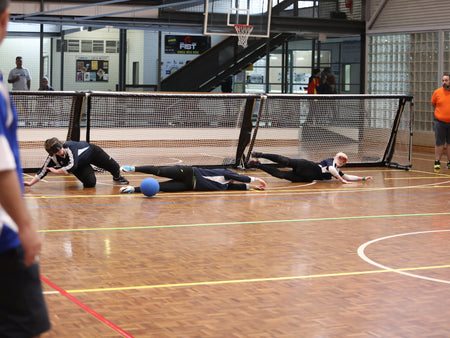 Goalball competitors diving for a ball during a match