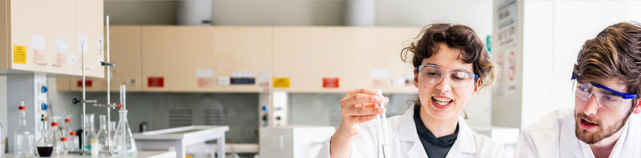 Two scientists in a lab setting, one holding a beaker and the other looking on. RMIT University