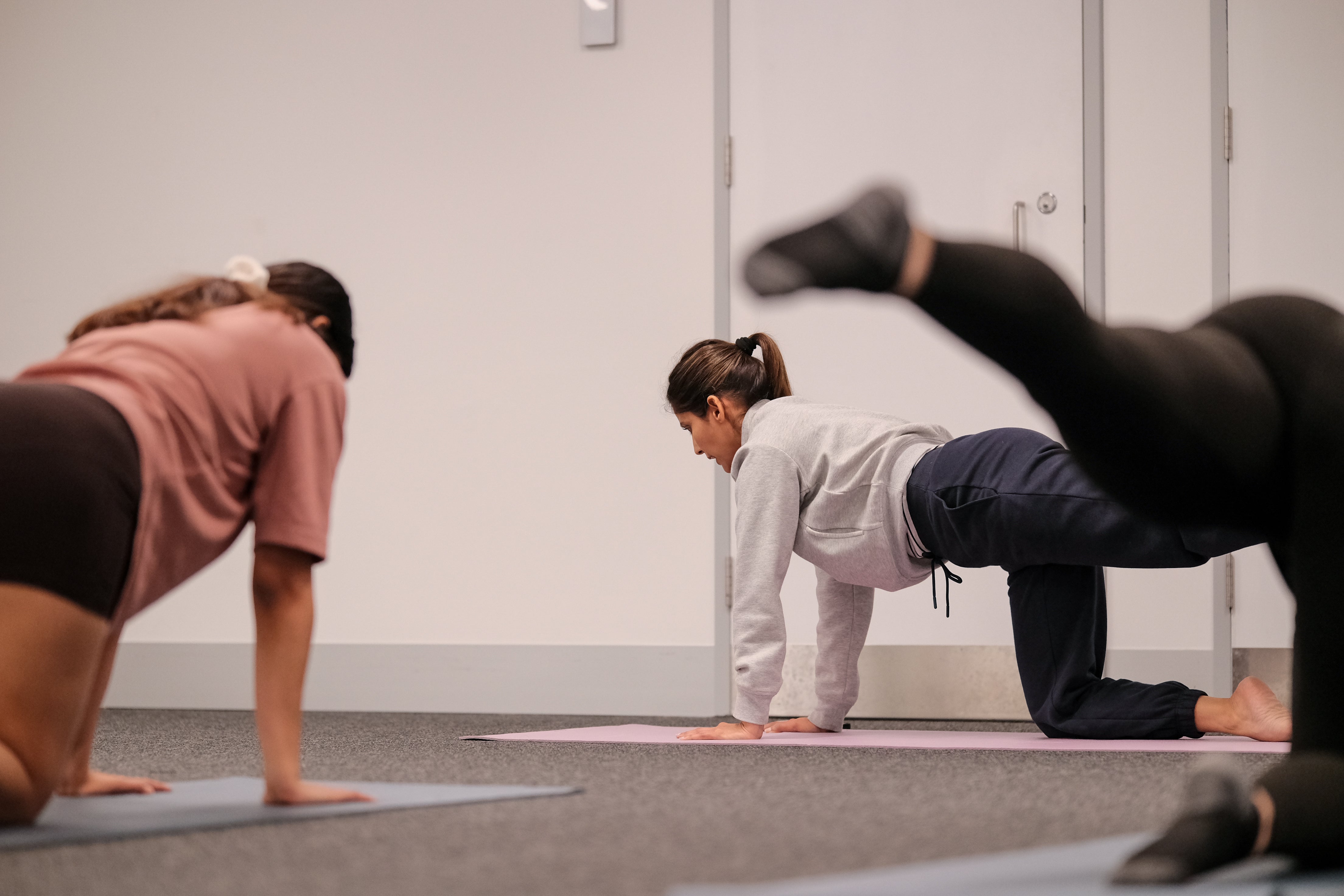 Participants and instructor performing a kneeling yoga pose