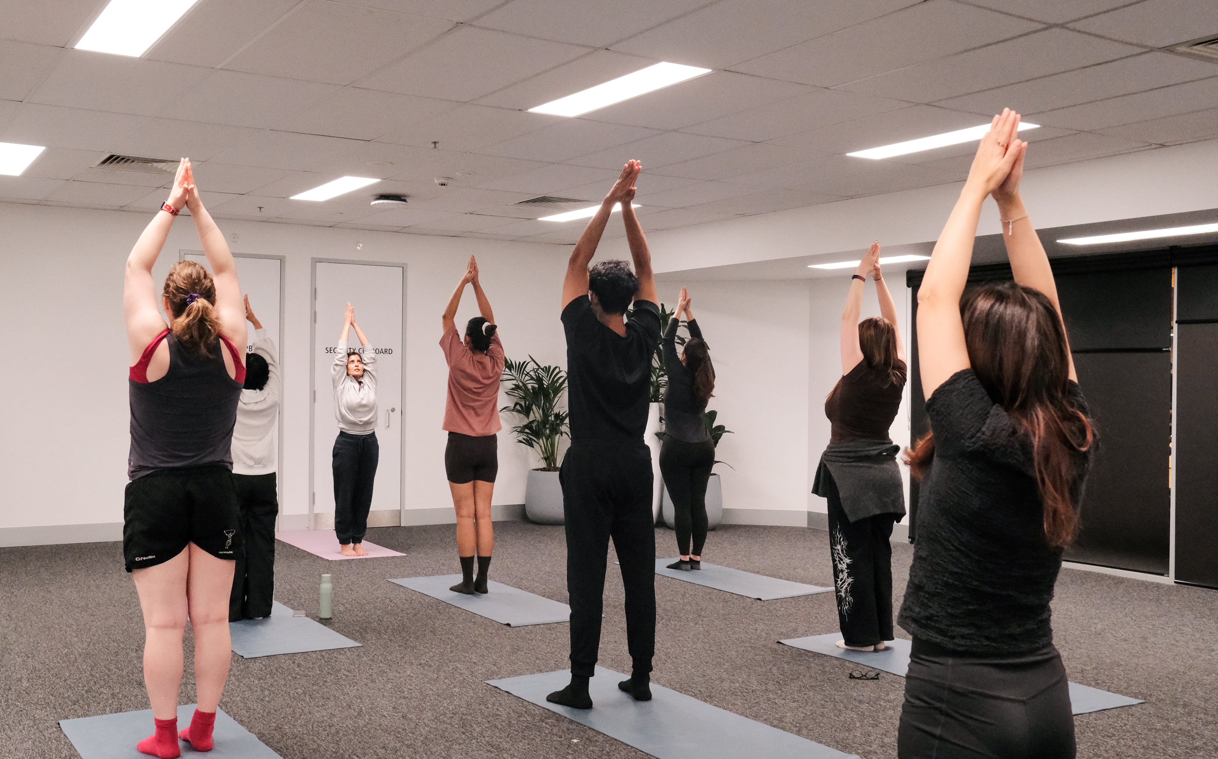 participants and instructor performing a standing overhead yoga pose
