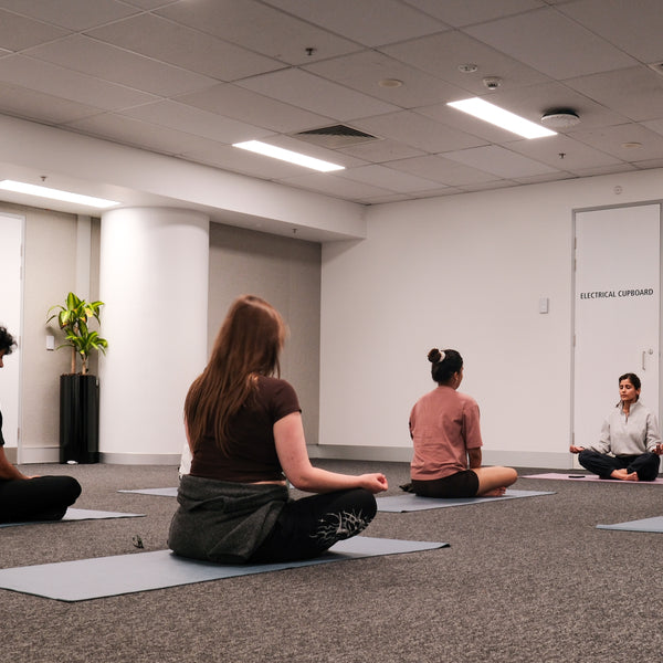 Participants and yoga instructor taking part in a crossed legs yoga session pose