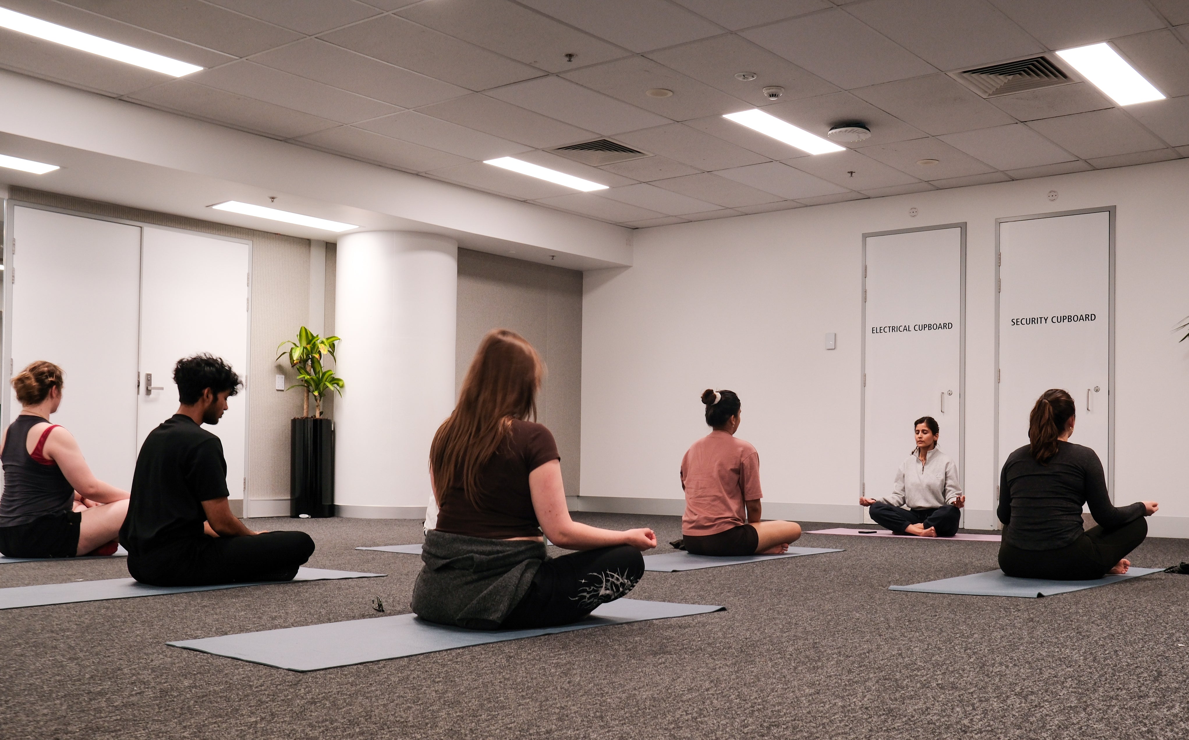 Participants and yoga instructor taking part in a crossed legs yoga session pose