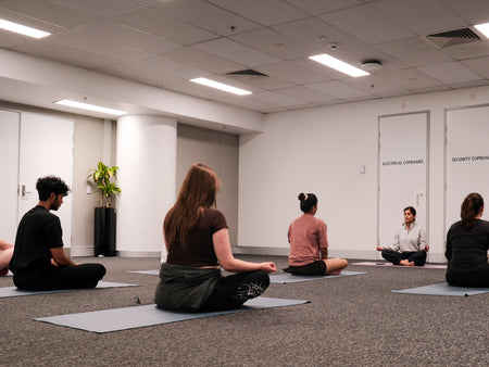 Participants and yoga instructor taking part in a crossed legs yoga session pose