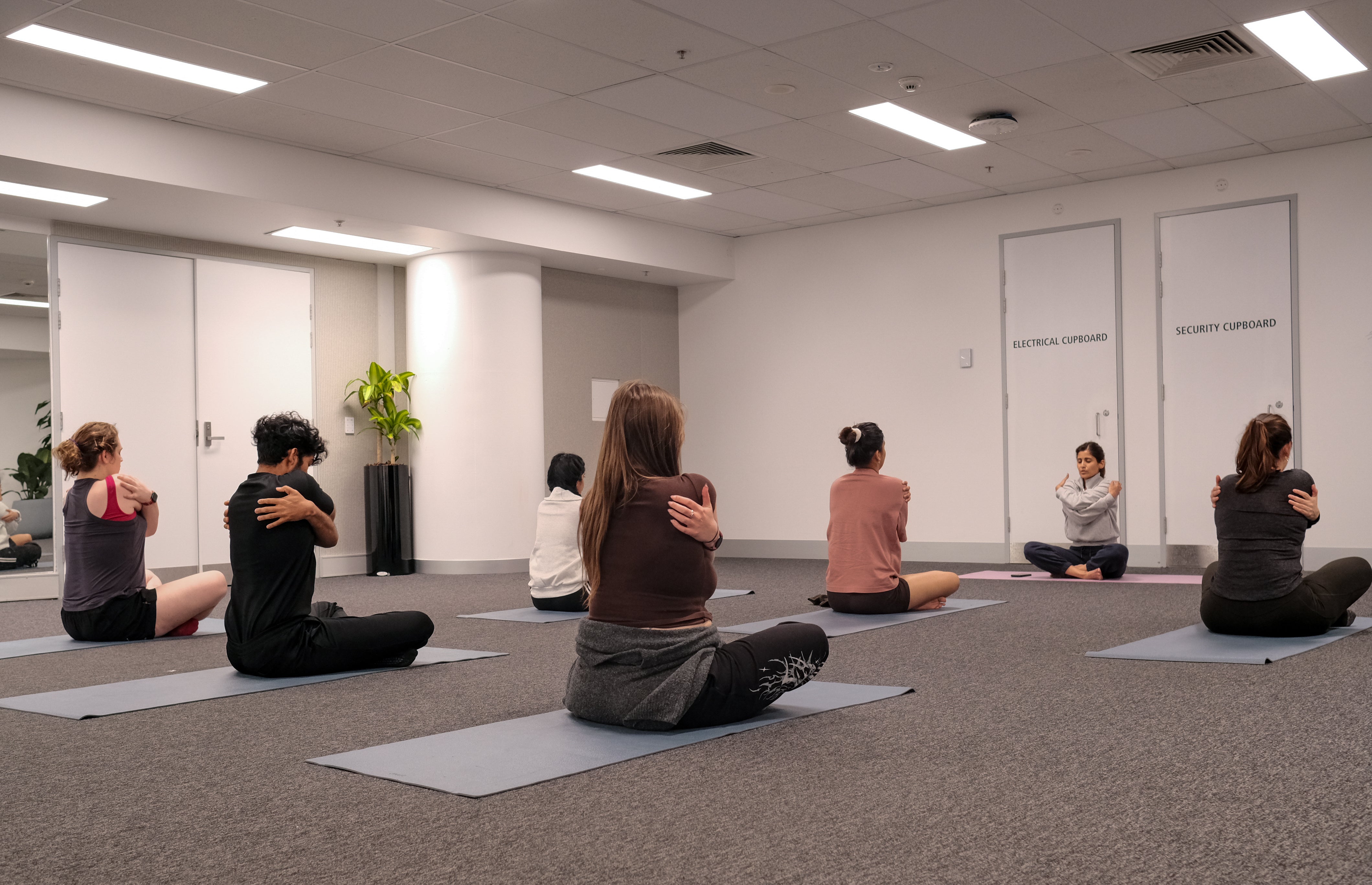 Participants and yoga instructor taking part in a crossed legs yoga session pose