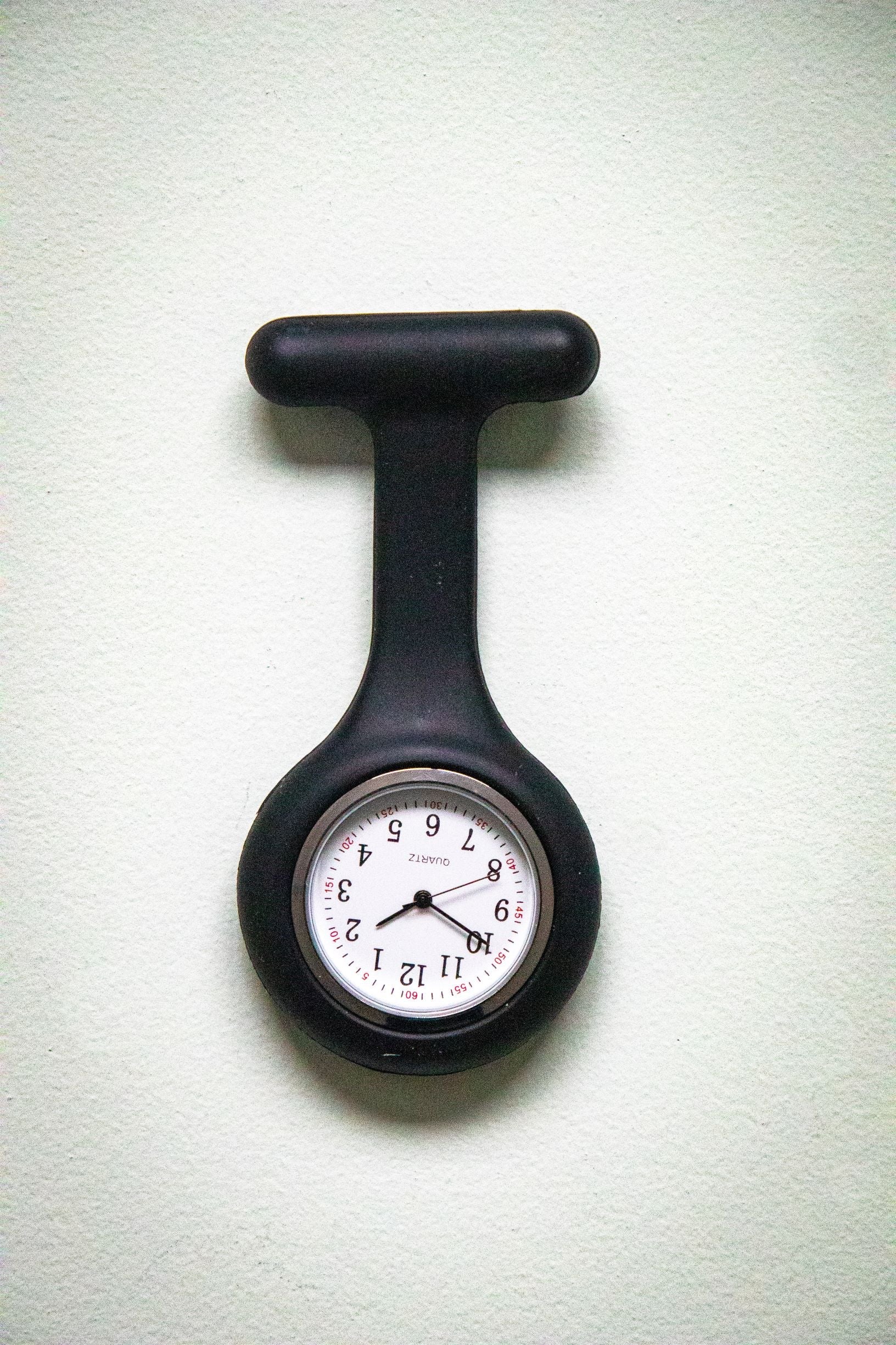 Front view of the RMIT Store black fob watch, featuring a white clock face with black numbers and three black hands, enclosed in a black silicone case.