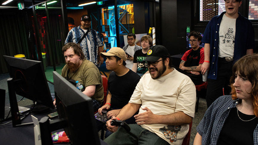 Group of people playing video games in a casual setting with multiple monitors in the RMIT Games Hub.