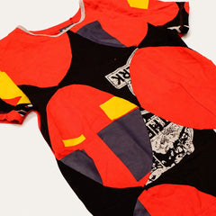 Blinking Stars fashion-student designed upcycled tee from RMIT Store, featuring a red upcycled short-sleeve tee reconstructed with black, red and yellow geometric panels, oversized red circular appliqués and monochrome printed textile sections, shown in a close-up showing reconstructed seams, appliqué, panel work and surface details on a light studio background.