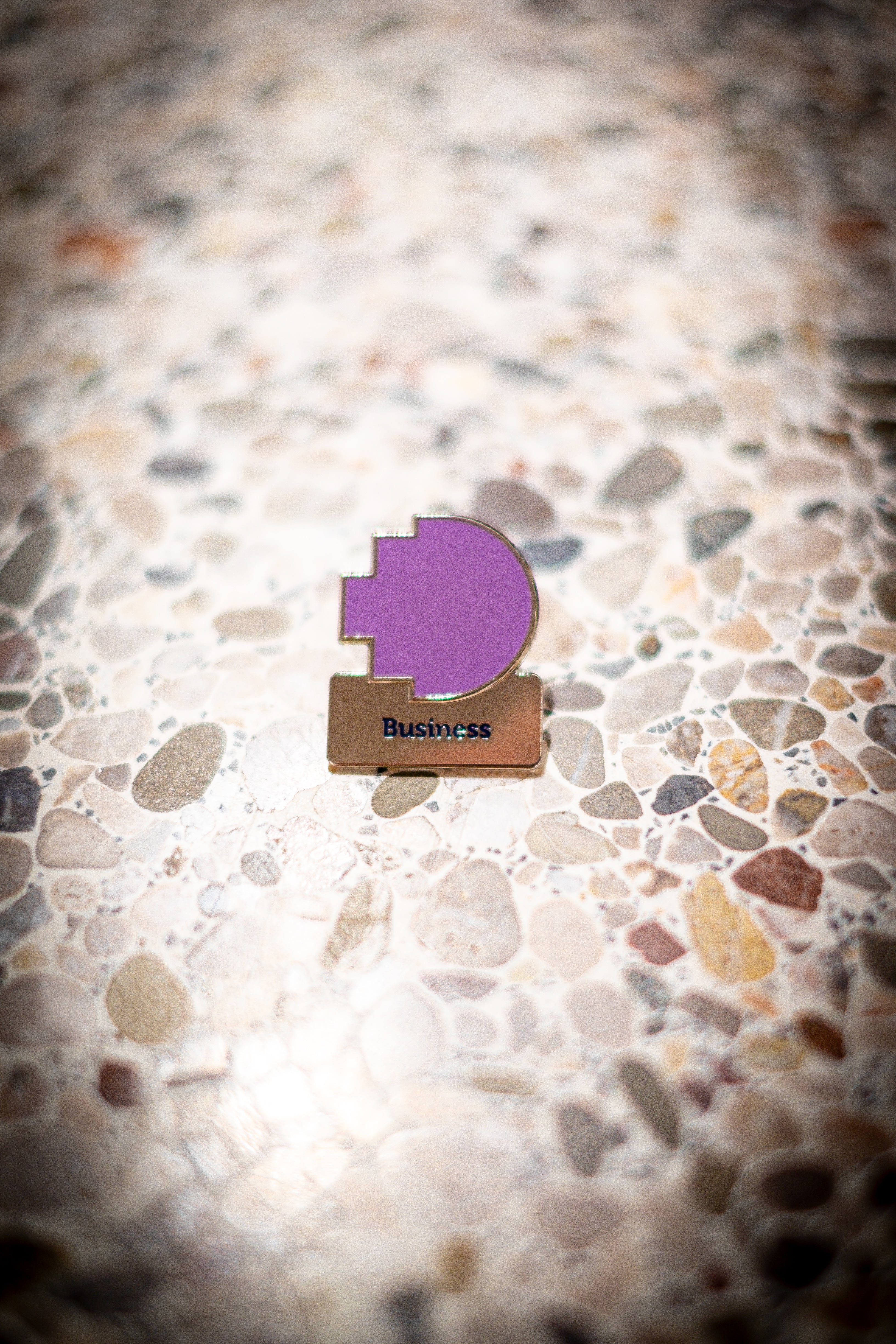 Business discipline pin featuring a purple pixelated logo above a silver square with 'Business' text, resting on a light marble background, available at the RMIT Store.
