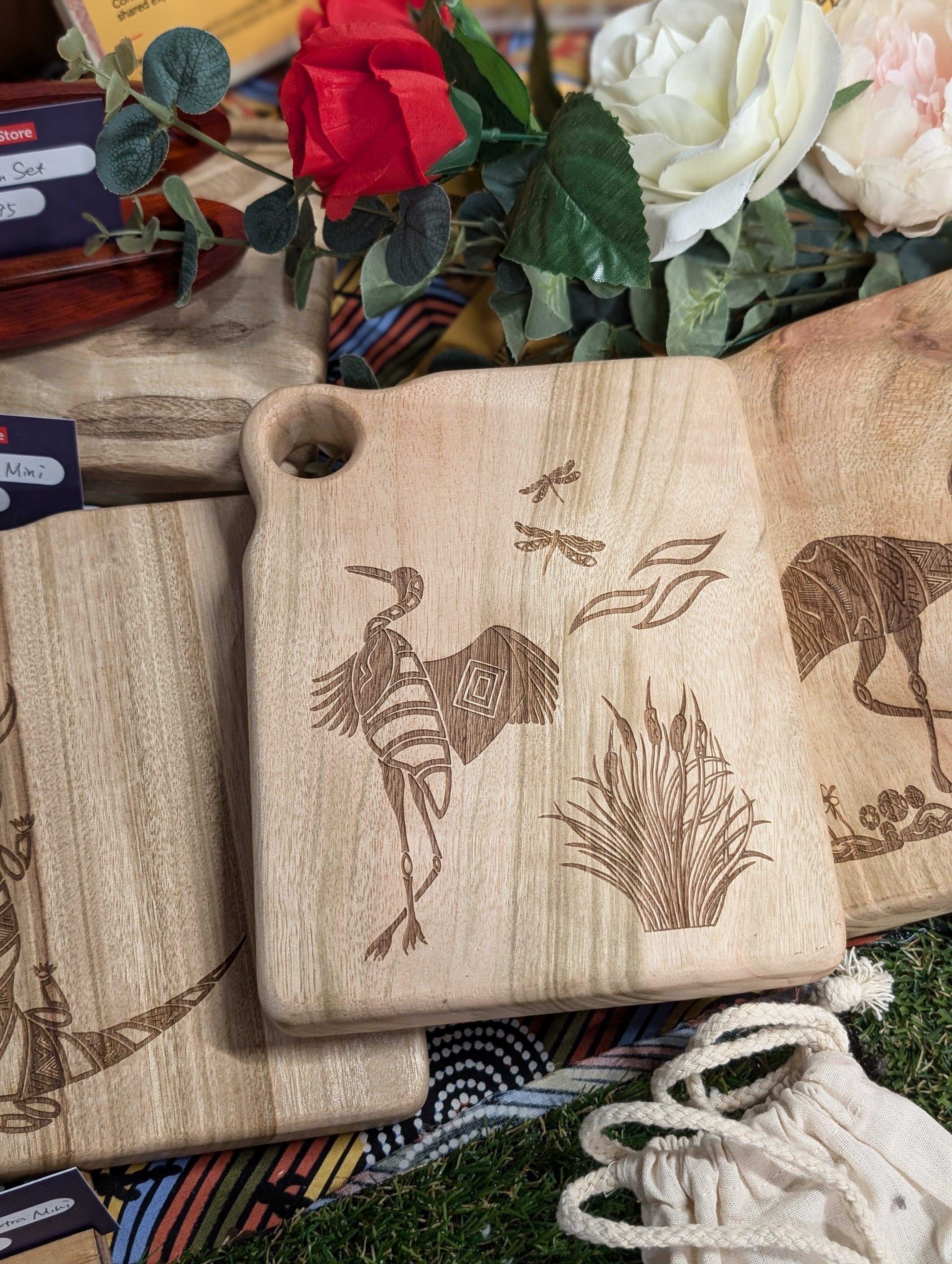 RMIT Store Camphor Laurel Board Extra Mini Rectangle with a crafted depiction of Garrok the Brolga and a stylised plant design, set against a vibrant backdrop of artificial flowers and herbal motifs.