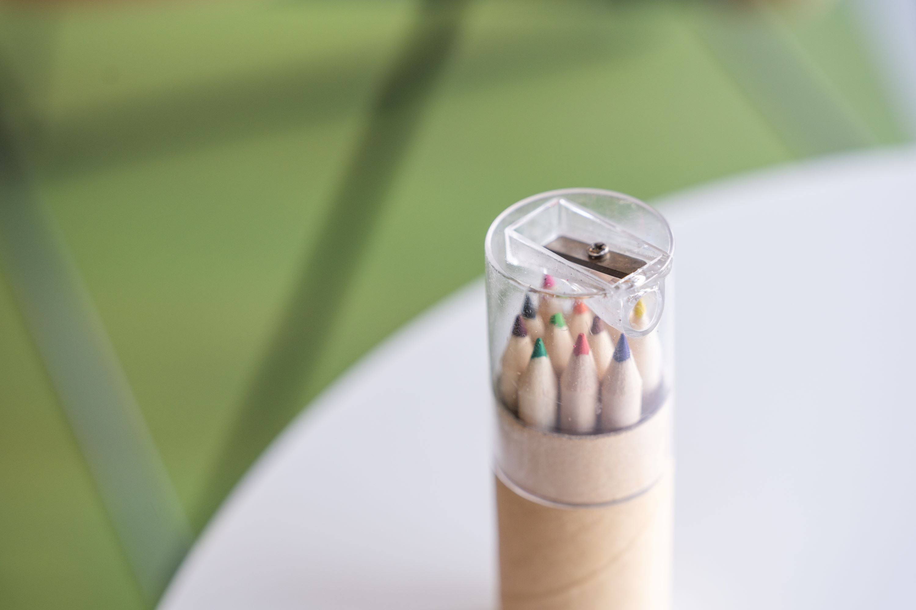 A pack of colourful pencils from the RMIT Store standing upright on a plain tabletop, with a sharpener on top of the pencil barrel.