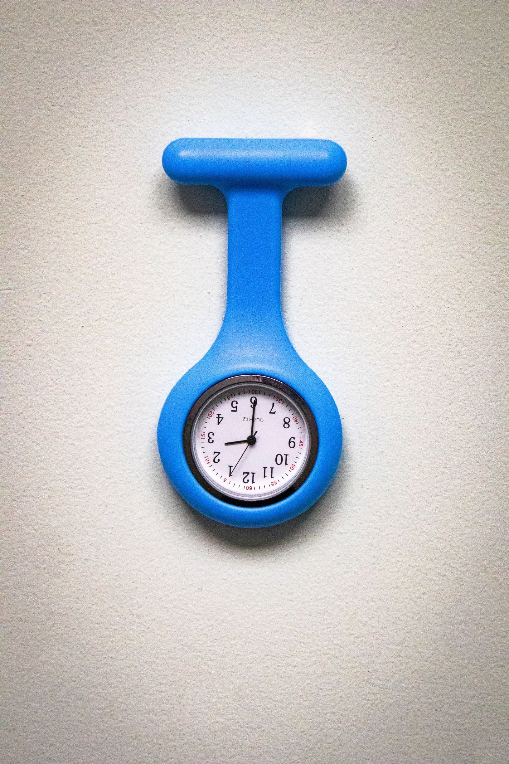 Front view of the RMIT Store light blue fob watch, featuring a white clock face with black numerals and three black hands, enclosed in a light blue silicone case.