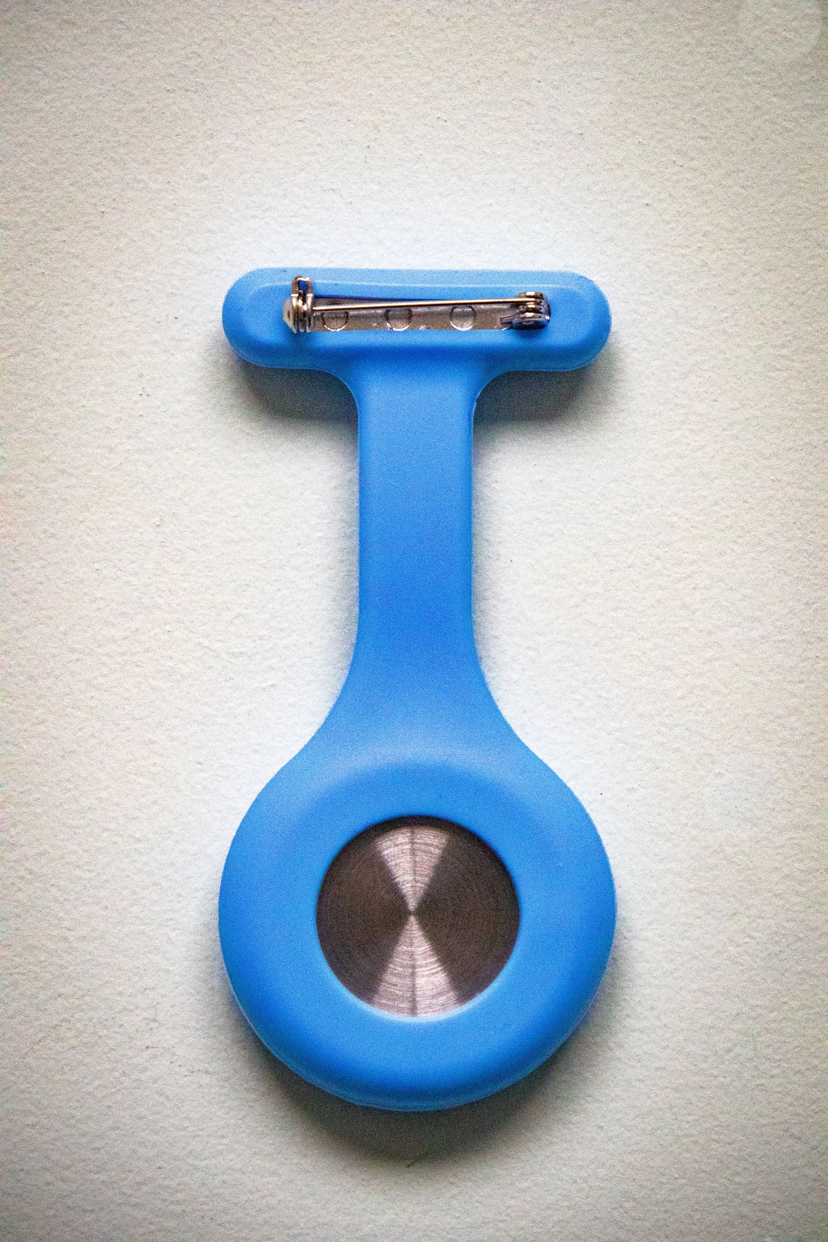 Rear view of the RMIT Store light blue fob watch, showing a smooth matte silicone casing with a silver pin clasp at the top. 