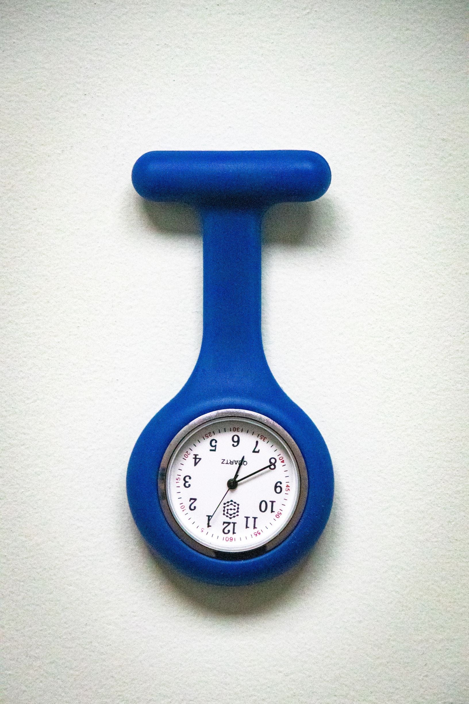 Front view of the RMIT Store navy fob watch, featuring a circular white clock face with black numbers and three black hands, encased in a smooth navy silicone cover.