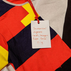 Geometrical Jigsaw 2 of 3 fashion-student designed upcycled tee from RMIT Store, featuring a red upcycled short-sleeve tee with large black, cream and red rectangular patchwork panels, yellow accents and contrasting sleeve sections, shown in a close-up showing reconstructed seams, appliqué, panel work and surface details on a light studio background.