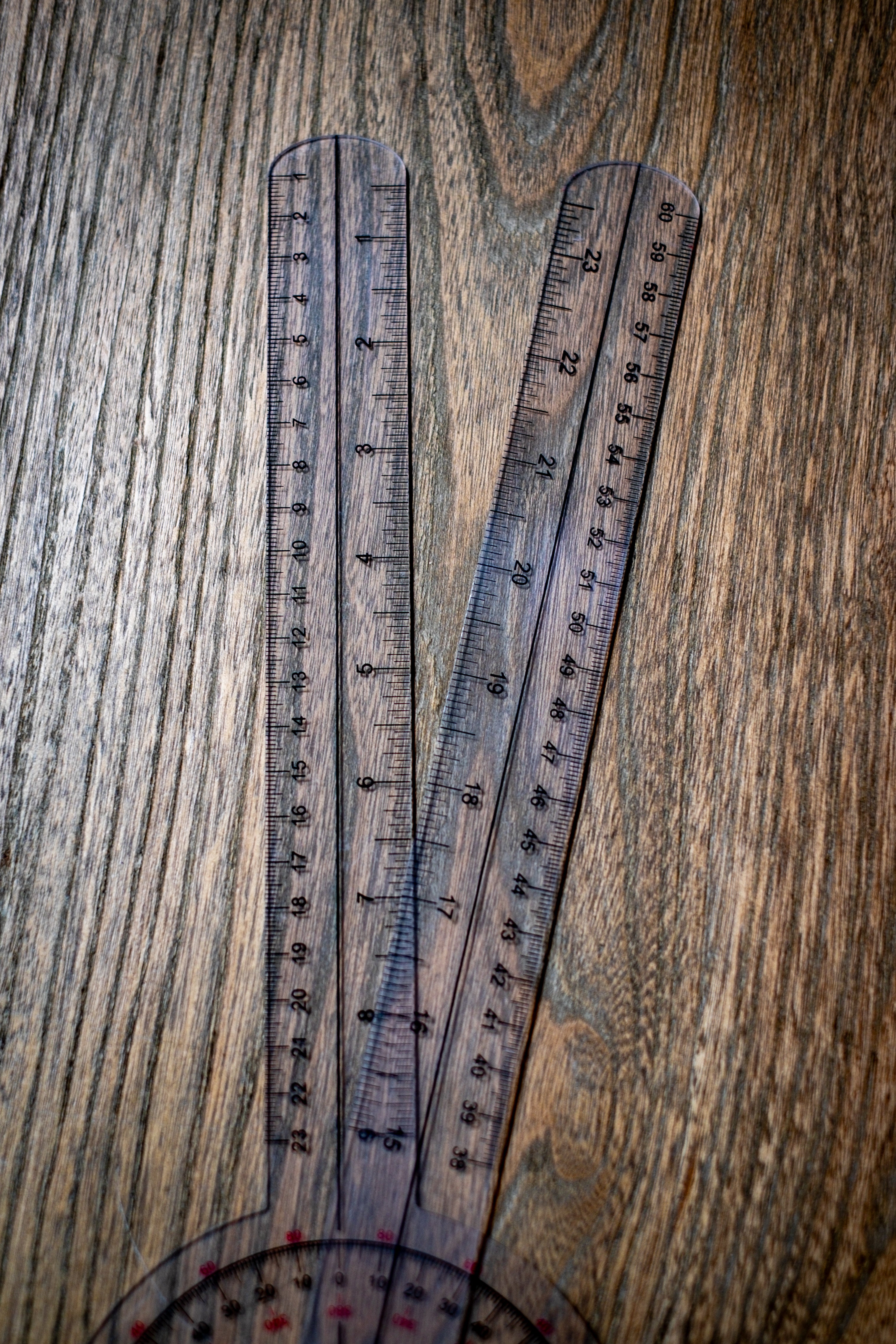 RMIT Store Gniometer, close-up view focusing on the transparent plastic handles, set against a neutral background. The image highlights the clear material, rounded ends, and precision hinge mechanism where the two handles meet. The close-up reveals fine manufacturing details, showcasing the tool’s quality and functionality for accurate angle measurements in educational or professional contexts.