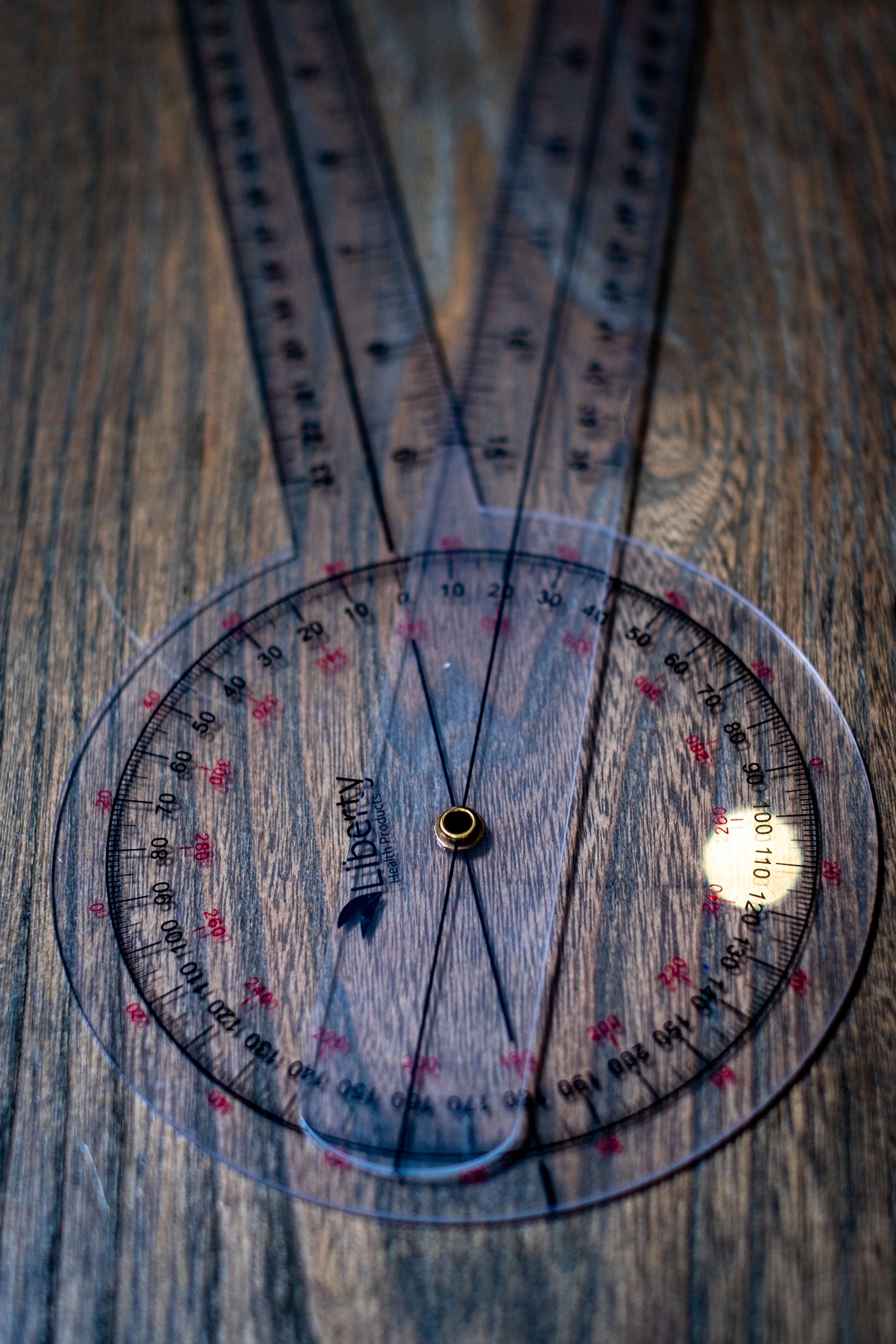 RMIT Store Gniometer, shown in a close-up top view with both handles open and extended on a neutral background. The transparent plastic body reveals detailed measurement increments etched along the curved angular scale. The image highlights the precision of the markings and the alignment of the extended arms, designed for accurate angle measurement in professional or educational settings.