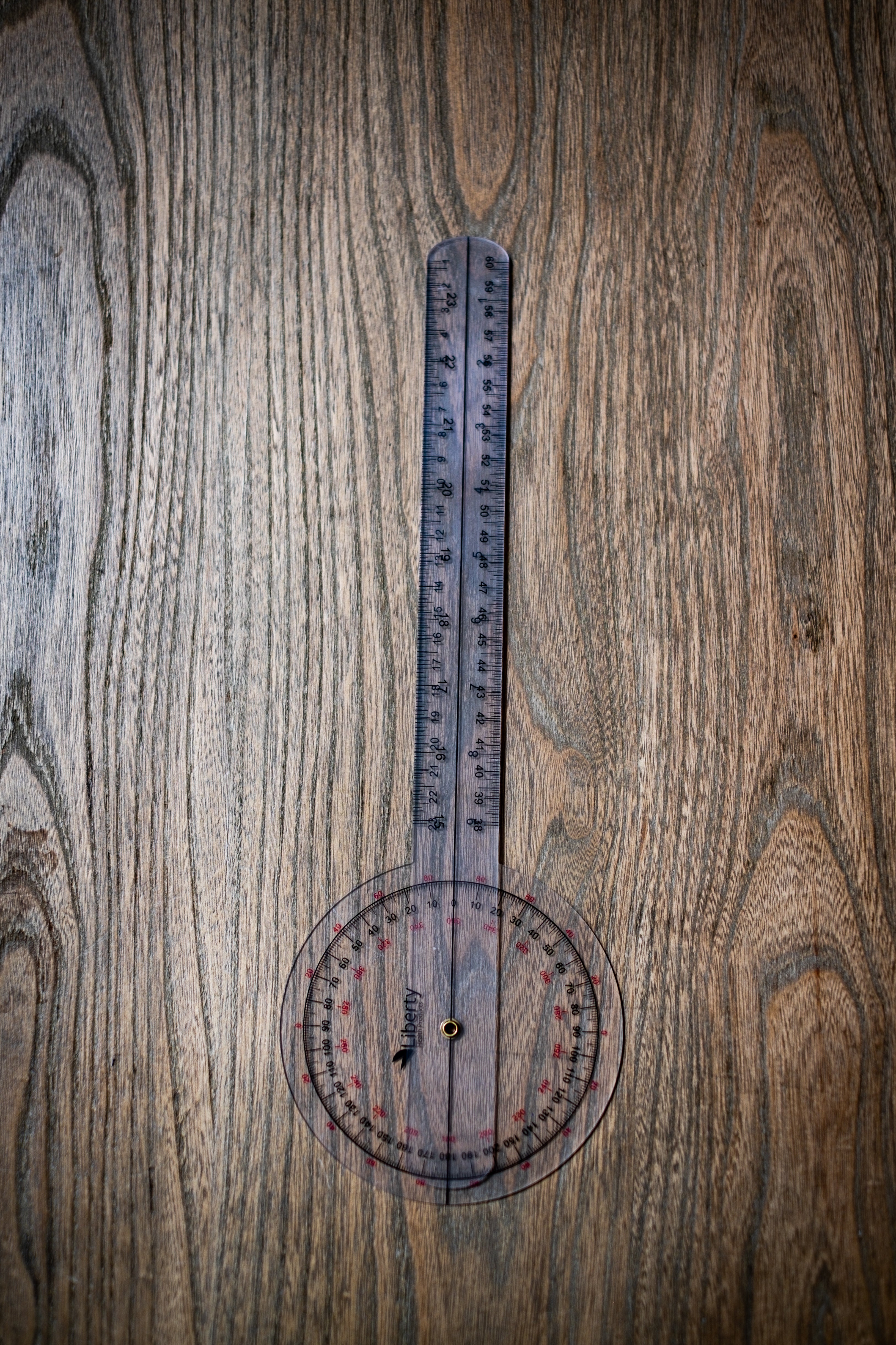RMIT Store Gniometer, shown from the top view with the two handles closed up, placed on a neutral background. The transparent body of the gniometer is visible, with the angular scale and measurement increments clearly marked along the edges. The closed handles emphasise the compact design of the device, making it easy to store and handle. This gniometer is designed for precise angle measurement, ideal for professional or educational use.