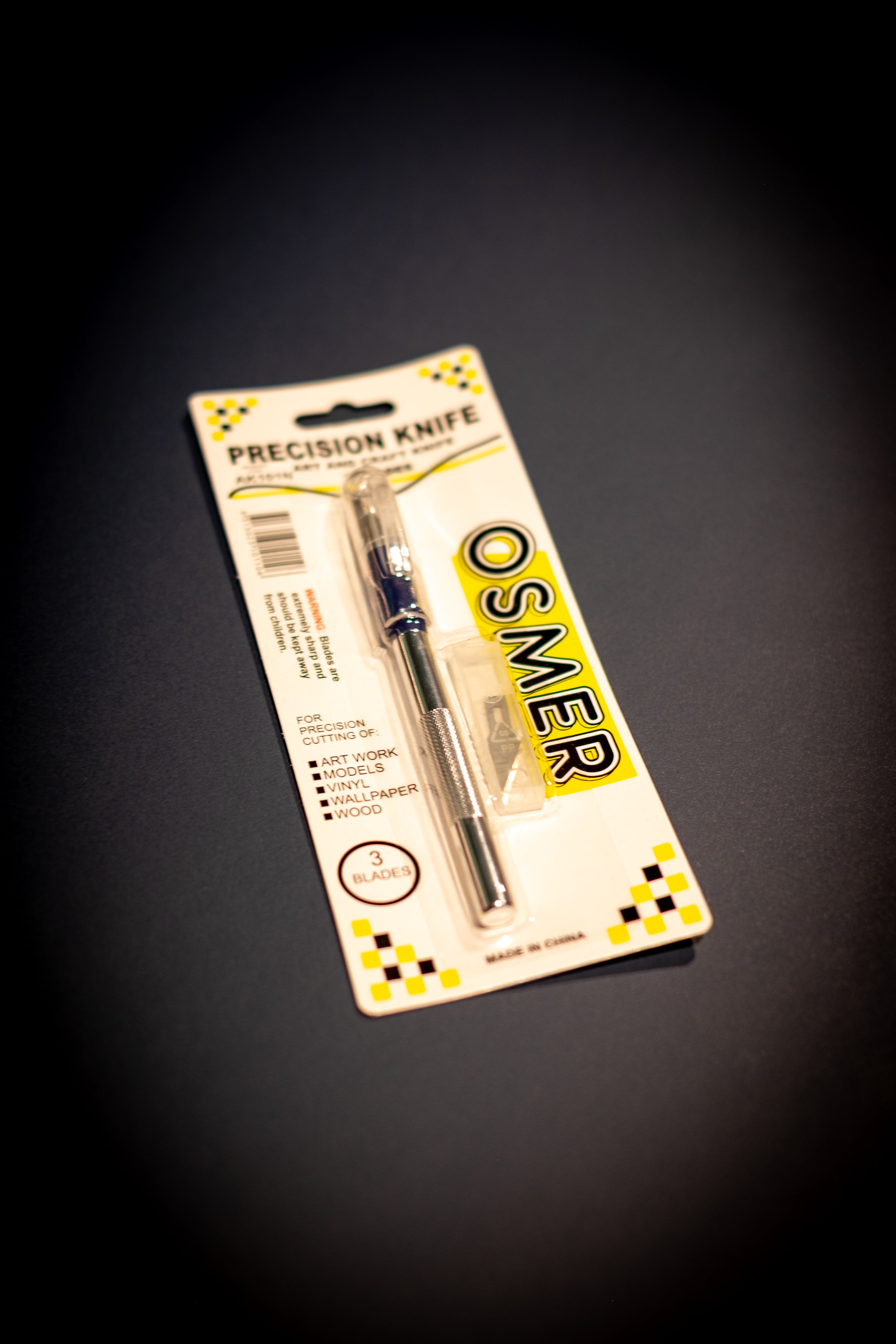 Interior Design and Decoration Kit featuring a precision craft knife in sealed blister packaging at RMIT Store, showing metal handle with textured grip, three replacement blades in a clear case, “PRECISION KNIFE” and “OSMER” branding, and cutting application icons.