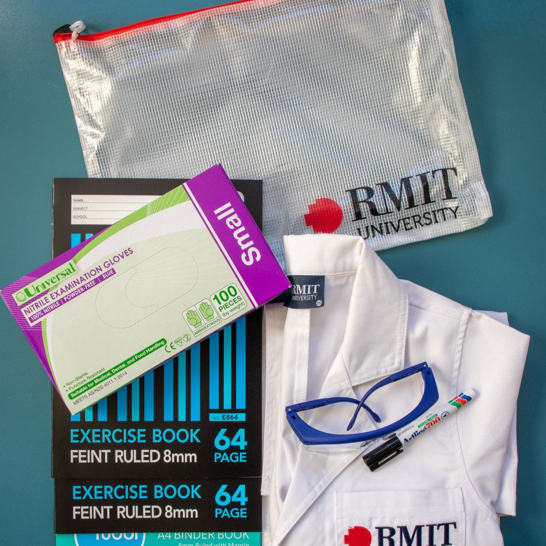 Complete RMIT Store Laboratory Technology Kit including nitrile gloves, exercise books, safety glasses, a marker, and a lab coat, all neatly arranged with an RMIT branded pouch.