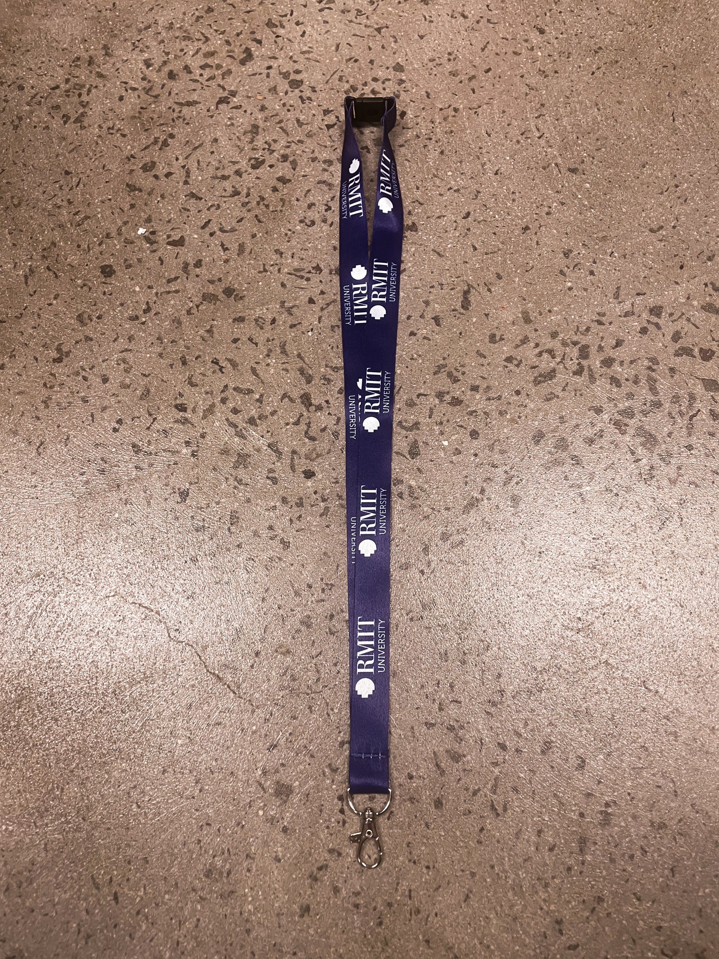 Navy RMIT Store lanyard featuring the RMIT University logo, displayed flat with a silver metal clip. Ideal for students and staff needing reliable identification accessories.