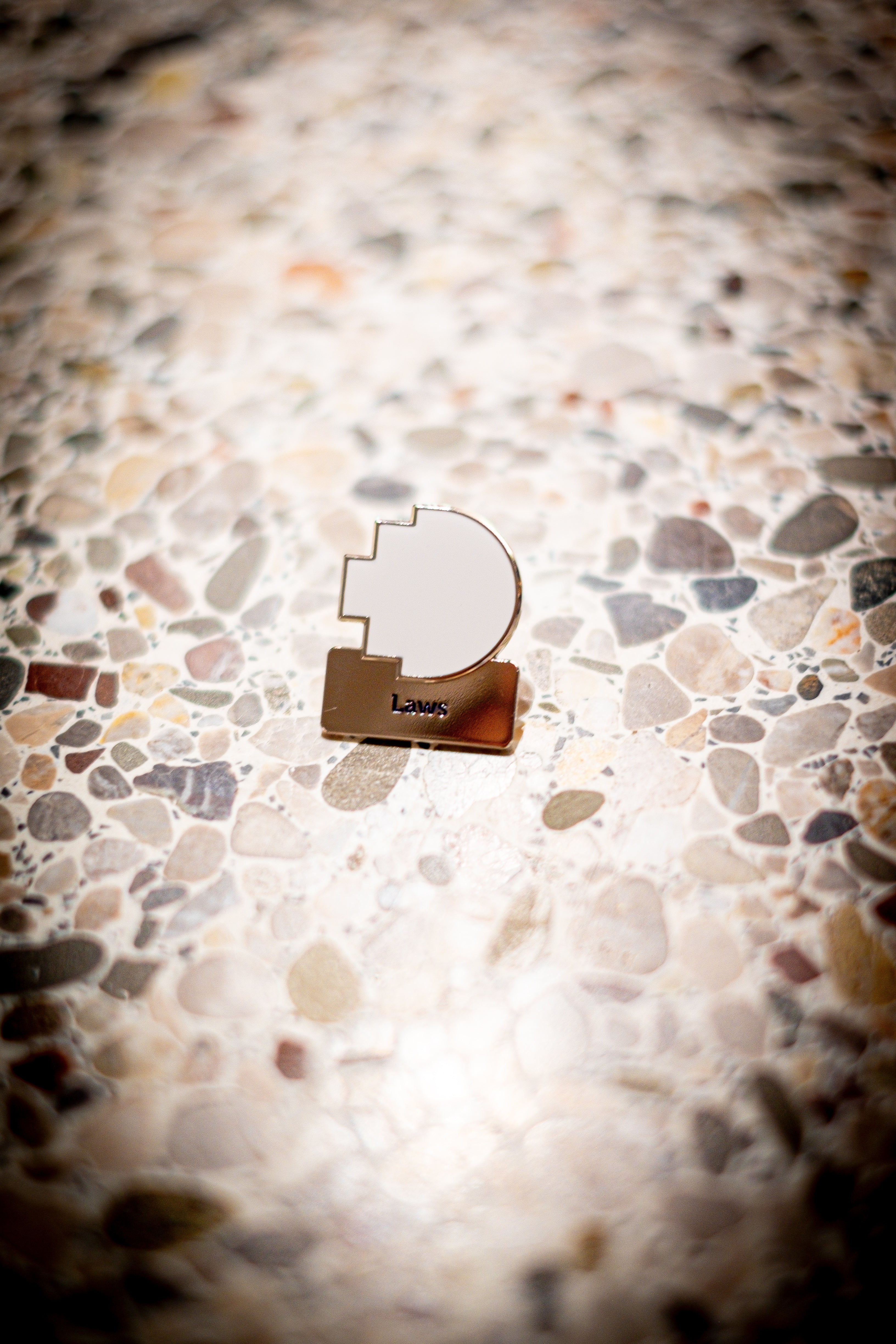 Laws discipline pin featuring a white pixel logo above a silver square with 'Laws' text, placed on a light marble background, available at the RMIT Store.