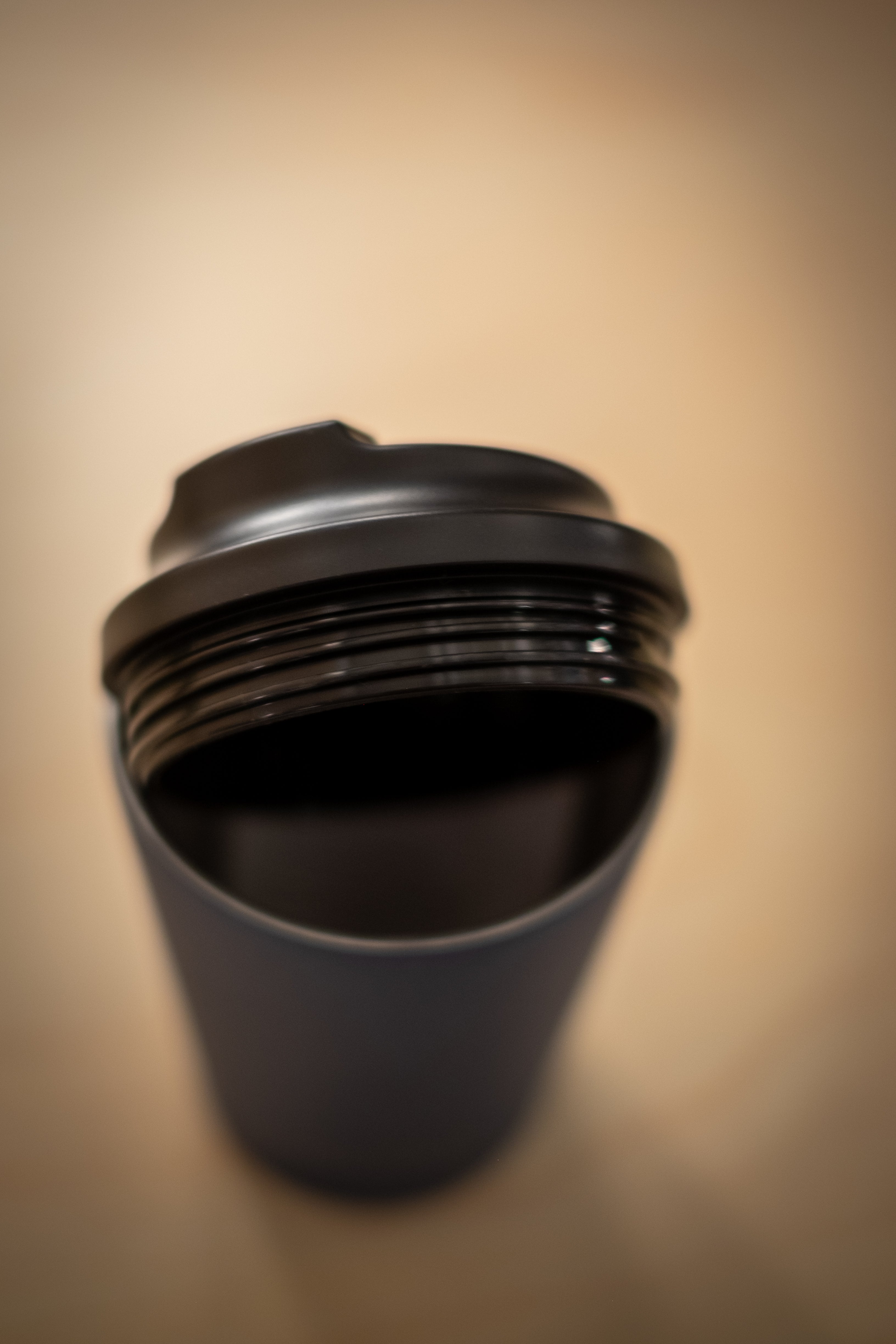 Made by Fressko x RMIT Reusable Cup in matte black photographed from above at RMIT Store, showing the screw-threaded rim and flip-lock drinking lid in close-up, with smooth curved lip, sealed threading detail, and softly blurred neutral background.
