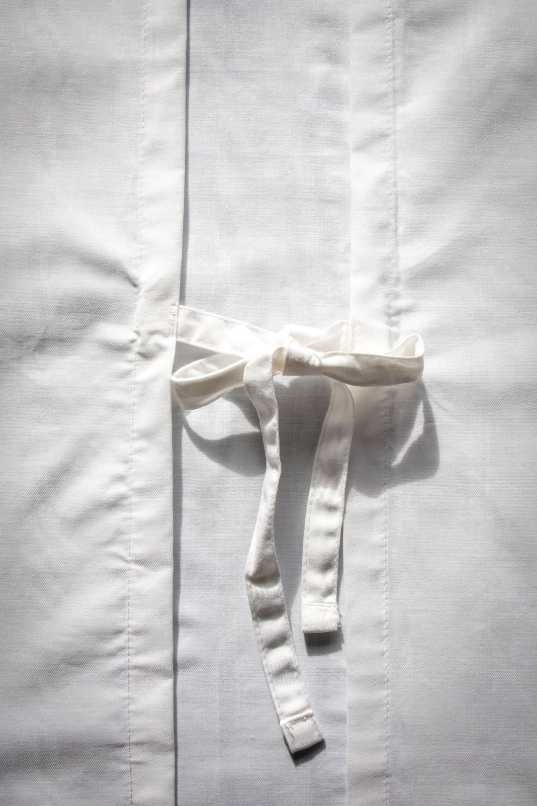 Close-up view of the fabric tie at the back of the white Medical Lab Gown from the RMIT Store. The tie is used to secure the gown, highlighting its functional design. 