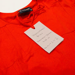 Monochromatic Bricks fashion-student designed upcycled tee from RMIT Store, featuring a red upcycled short-sleeve tee with subtle tonal red stitched panel lines forming an irregular brick-like pattern across the garment, shown in a close-up showing the attached white swing tag and nearby reconstructed fabric details on a light studio background.
