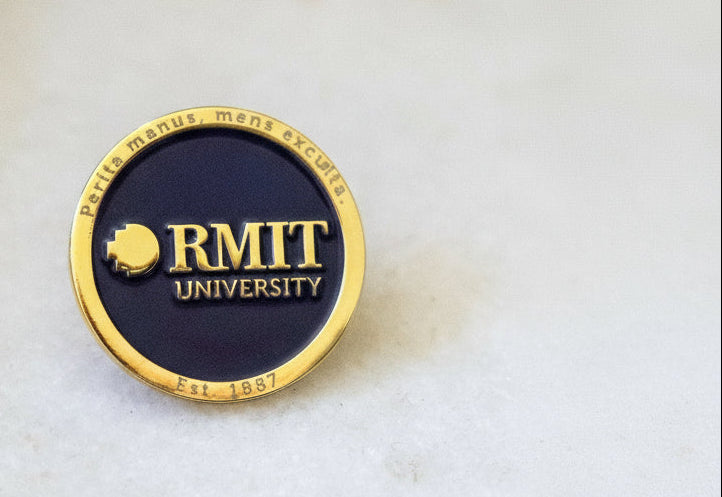 RMIT University badge with gold rim and navy center on a light background