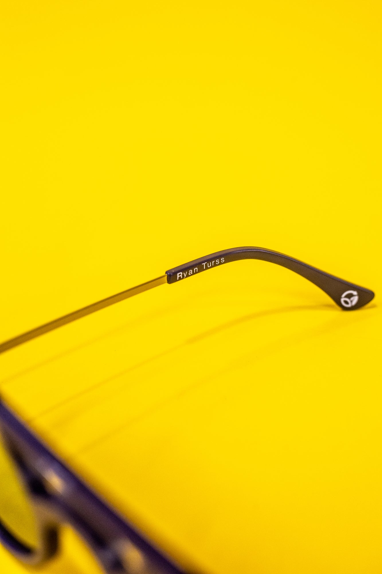 Close-up showing a small portion of navy blue pixelated sunglasses and one leg with the white printed 