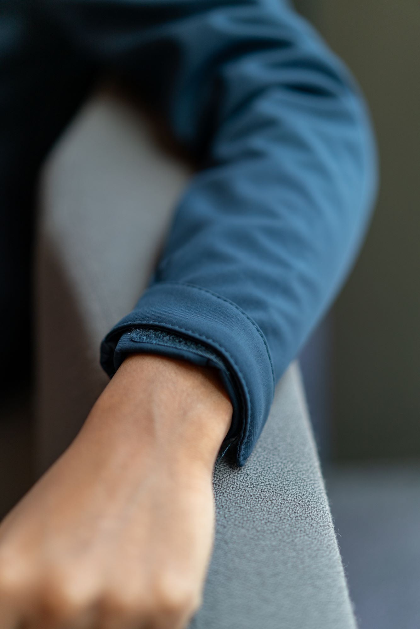 Close-up zoomed-in view of the adjustable cuff sleeve on a navy softshell jacket from the RMIT Store, featuring a black velcro strap with textured fabric and neat stitching details on the water-resistant material.