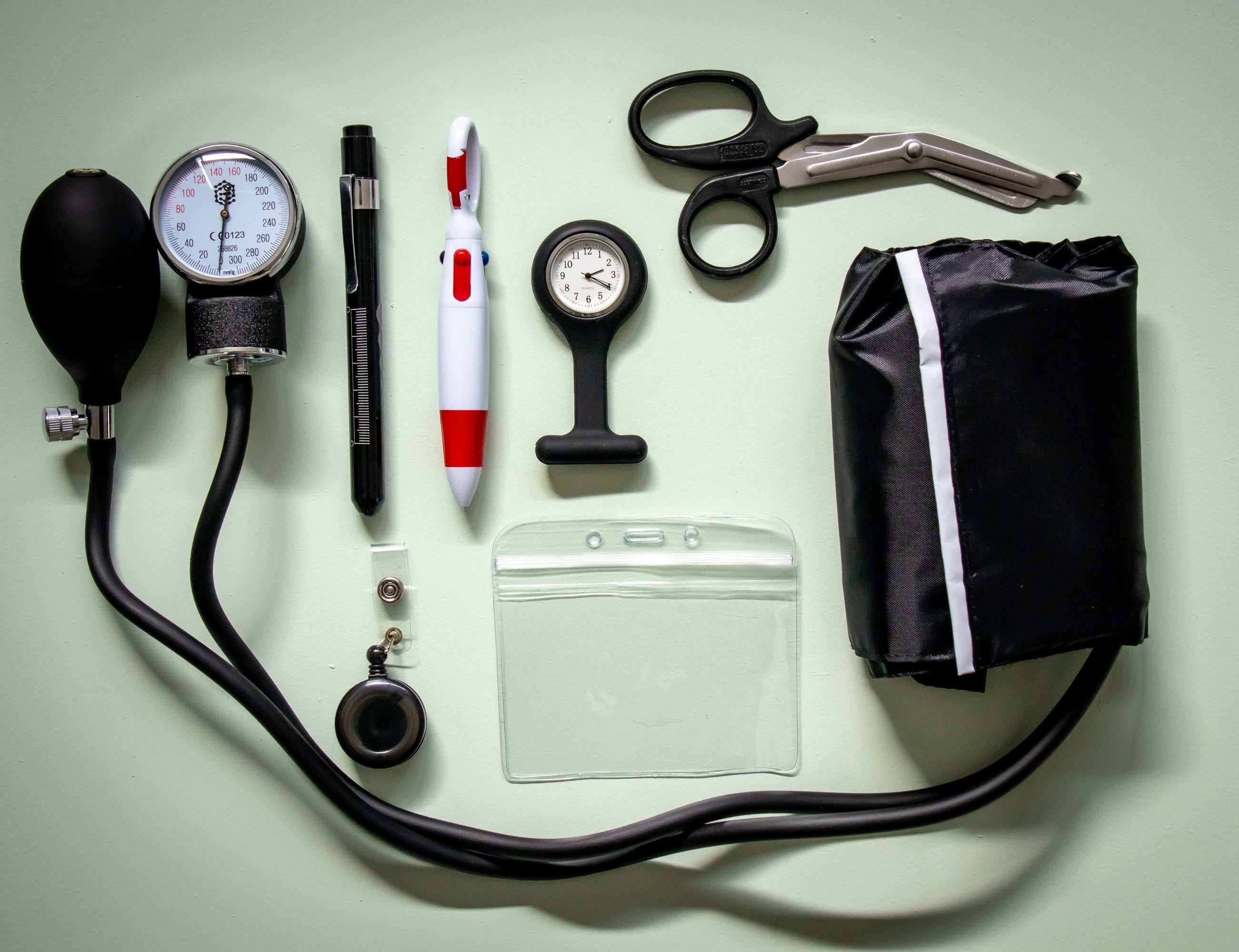 Comprehensive nursing kit from the RMIT Store displayed against a light teal background, including an aneroid sphygmomanometer, silicon nurses fob watch, pen light torch, universal scissors, 4 colour pen, retractable ID tag and card holder, and a clear large pouch.