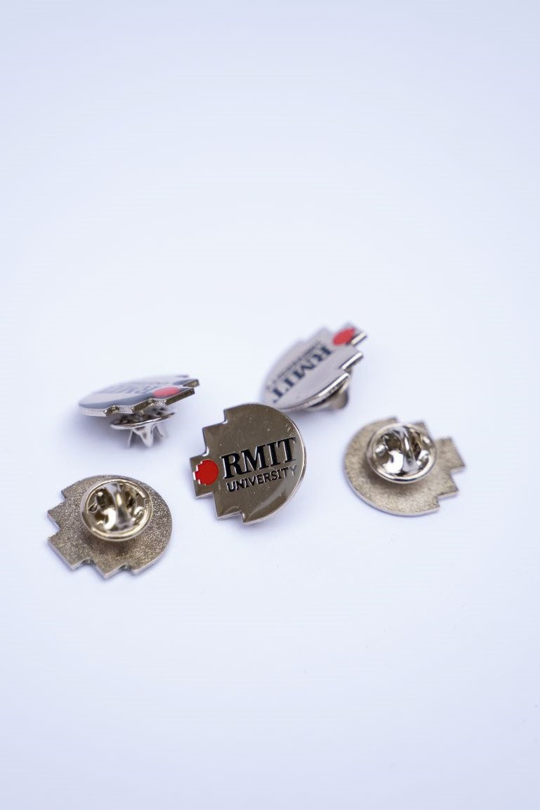 Set of RMIT Pixel Lapel Pins laid out on a white surface. Each pin presents the RMIT University branding in red and grey, available at the RMIT Store.