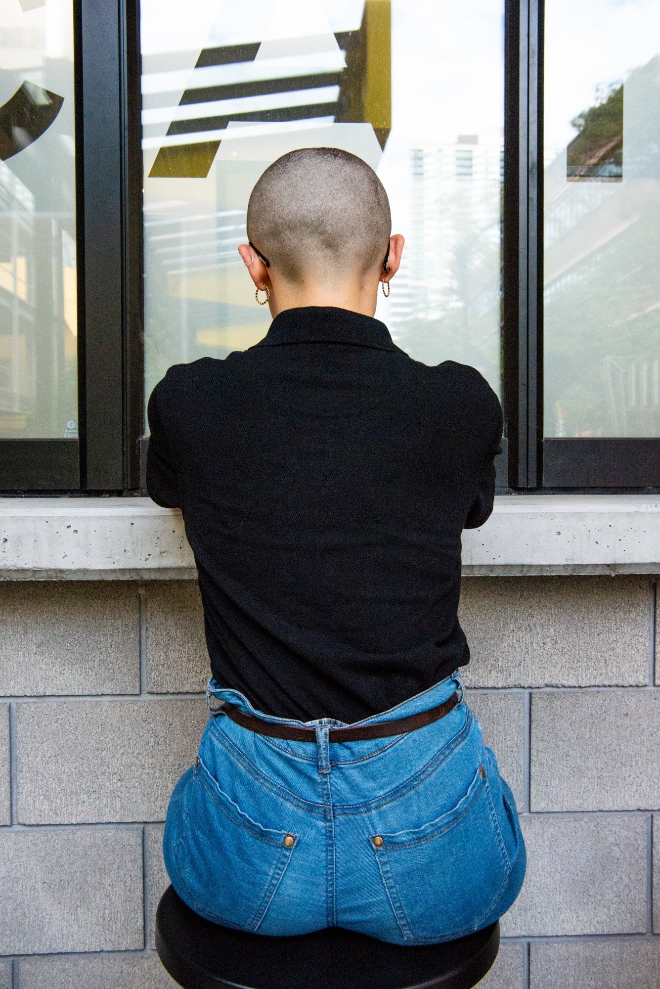 Rear view of a model in a black RMIT Polo, showcasing the classic cut and design details. The polo's back view emphasizes simplicity and style, another quality item from the RMIT Store.