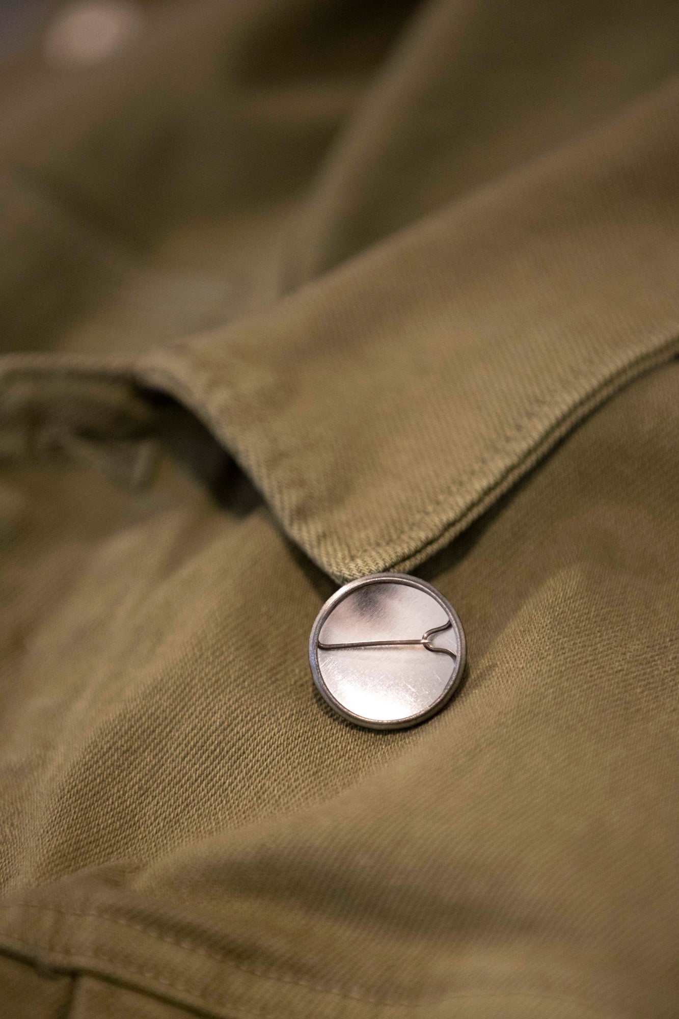 Close-up view of an RMIT University badge with a pin at the back for fastening. The focus is on the badge's pin attachment.