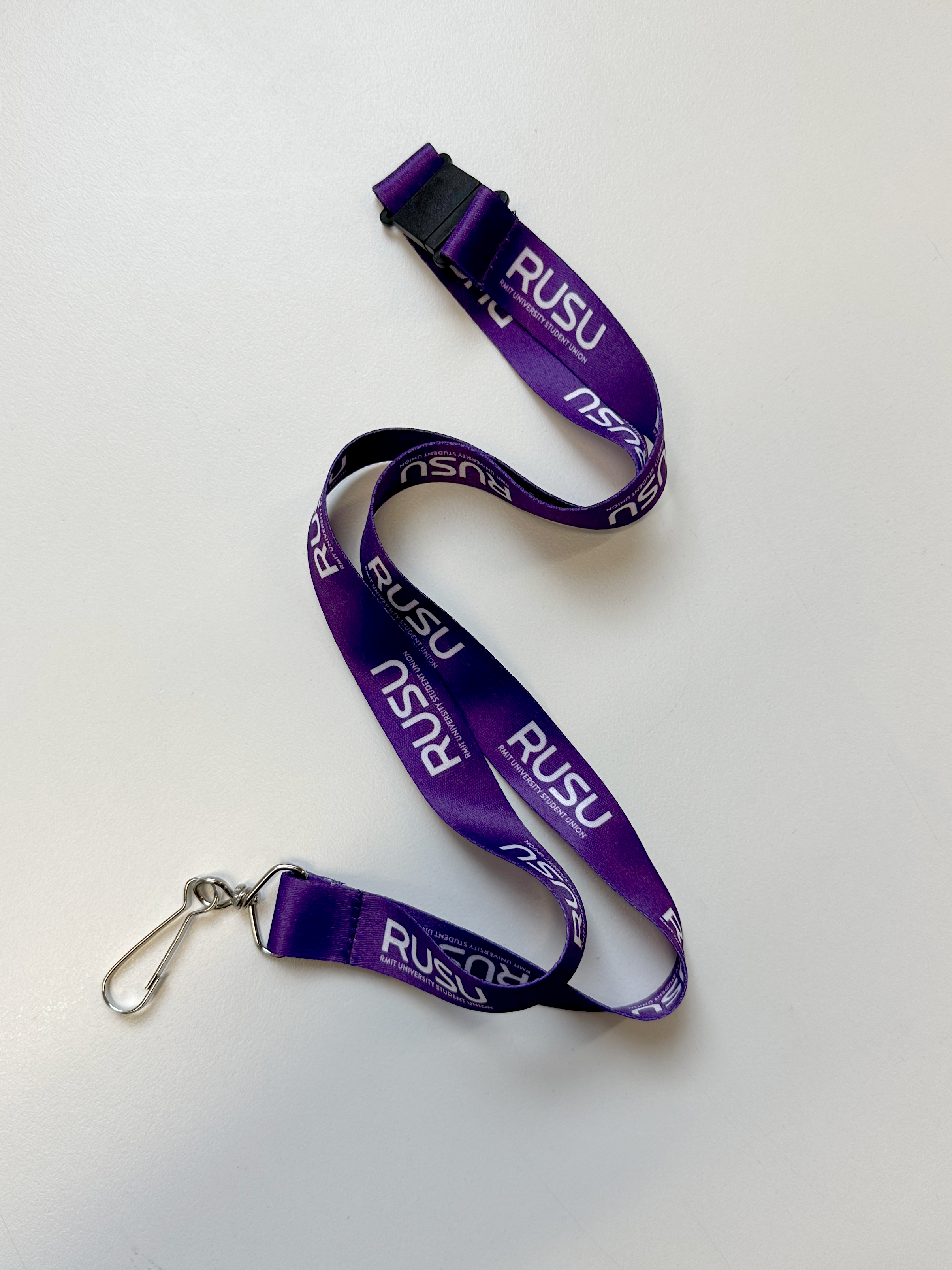 Purple RUSU lanyard from the RMIT Store with a silver metal clip, laid out on a white surface.