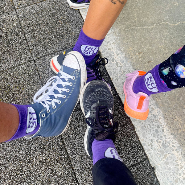 RUSU Socks in purple with a white circle with the RUSU logo. Worn in a group shot of 4 models.
