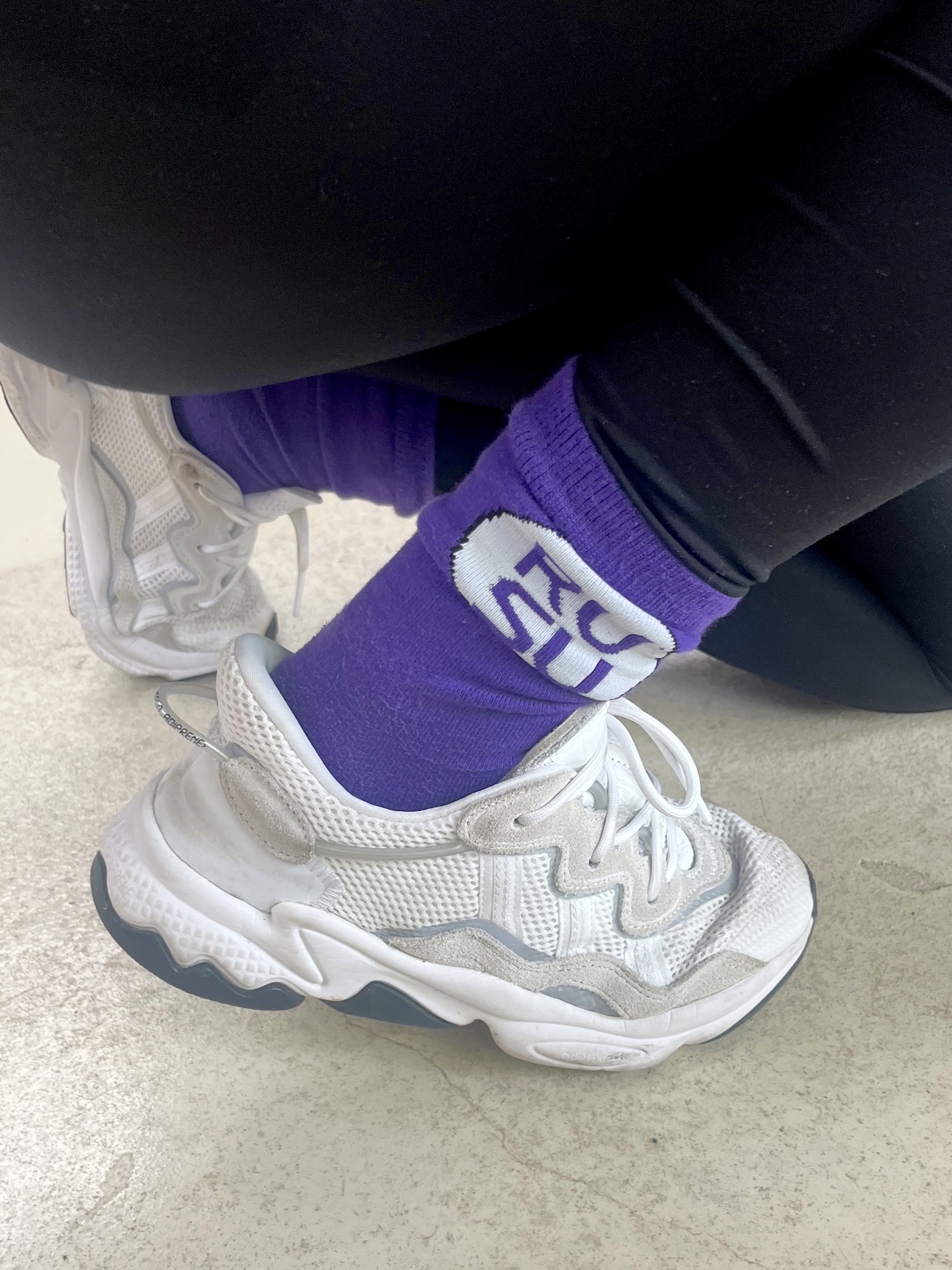 RUSU Socks in purple with a white circle with the RUSU logo. Modelled and photographed from the side.