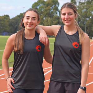 Two female models standing front view on running tracks wearing black RMIT Redbacks Singlets with red and black Redbacks logos on left chests, the model on the left resting her right arm on the right model’s shoulder, both smiling, subtle light black horizontal patterns visible on singlets. Available at the RMIT Store.
