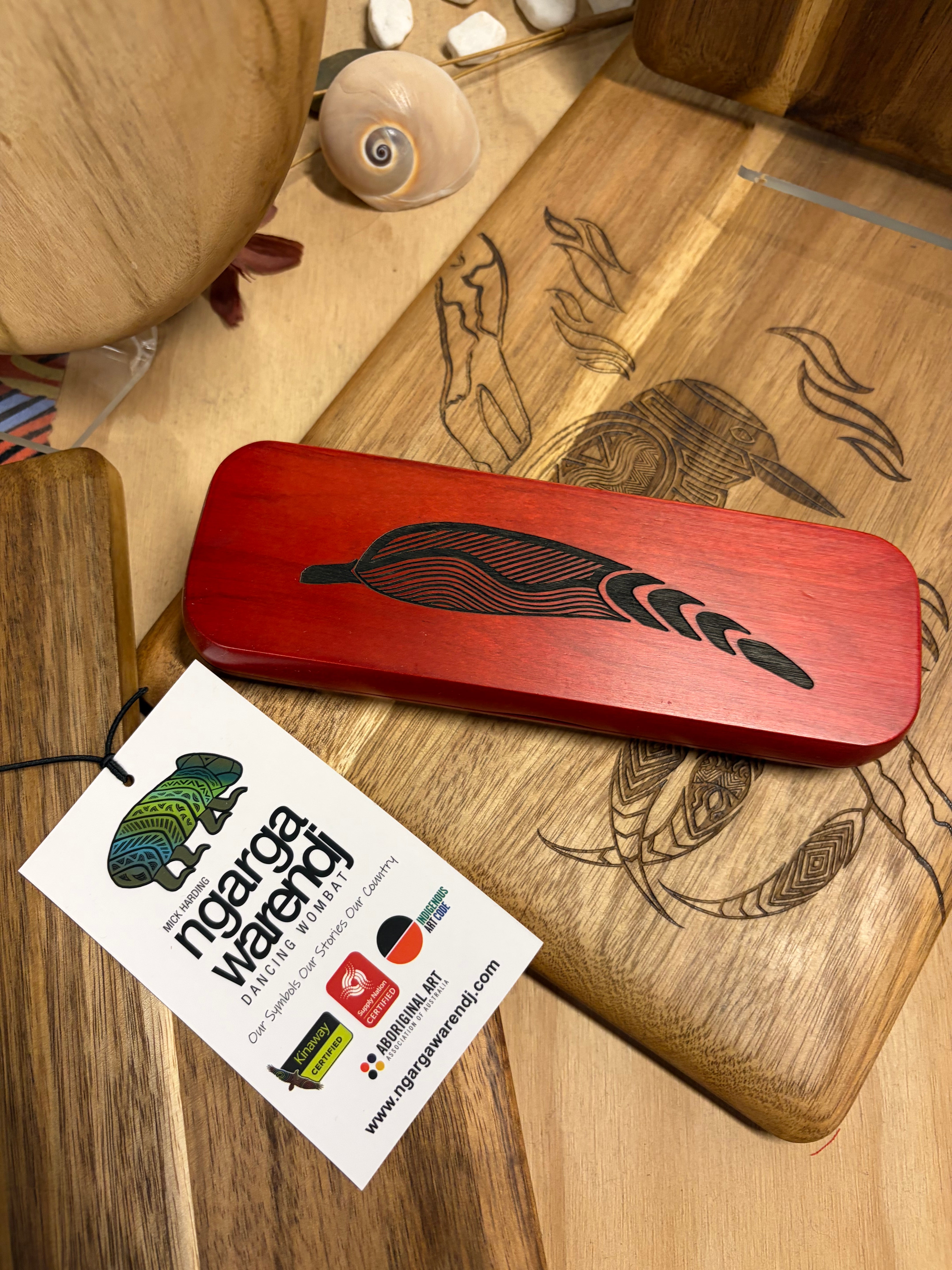 Rosewood Rectangular Pen Set featuring a polished reddish-brown oval wooden pen case with black laser-engraved flowing leaf and wave pattern, displayed at the RMIT Store, with no model present and visible natural wood grain beneath the engraved design.