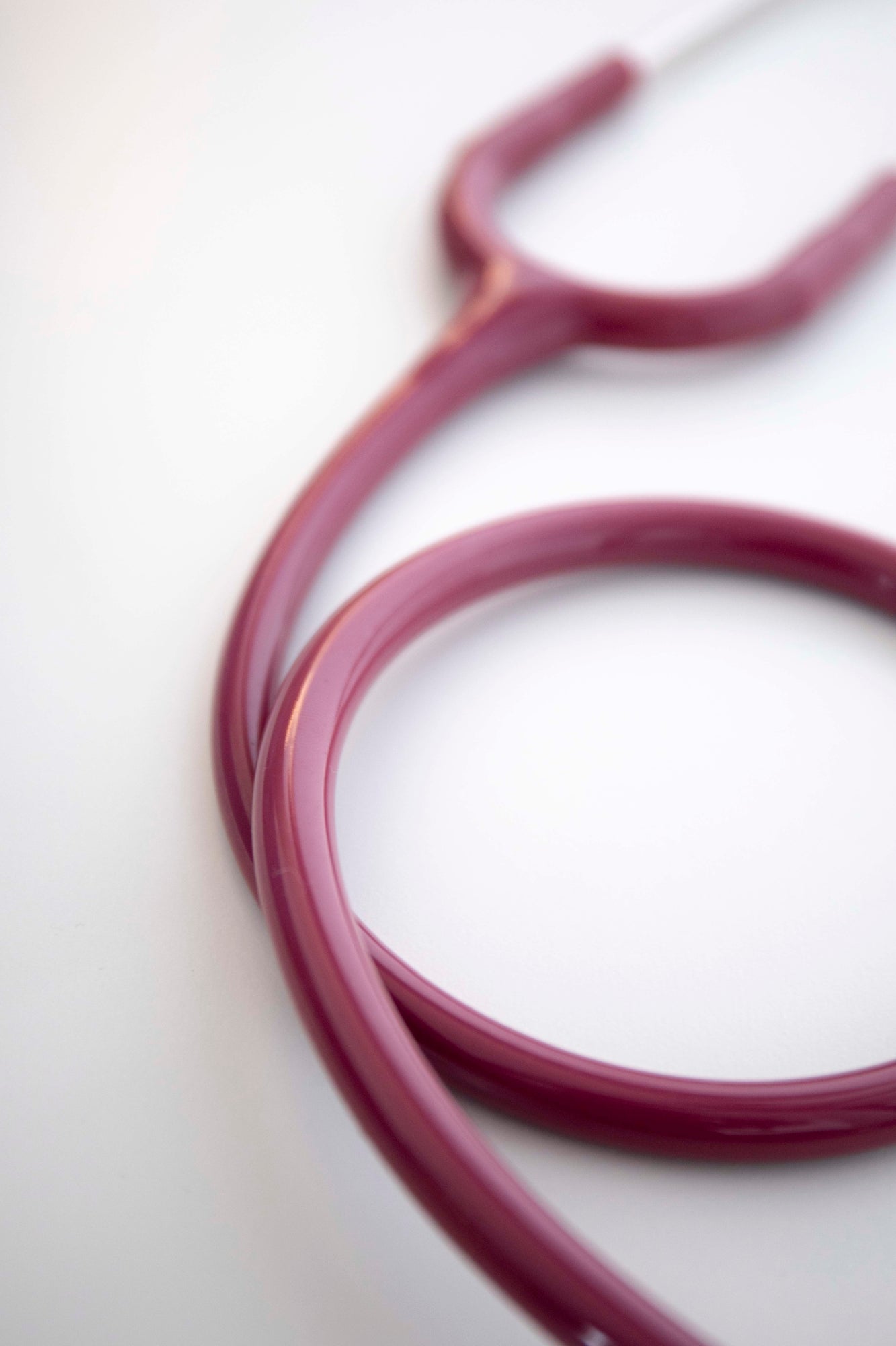 Purple stethoscope with silver tubing, fully visible and coiled in a circular shape on a light white surface; features a simple dual-head design and is sold through the RMIT Store.