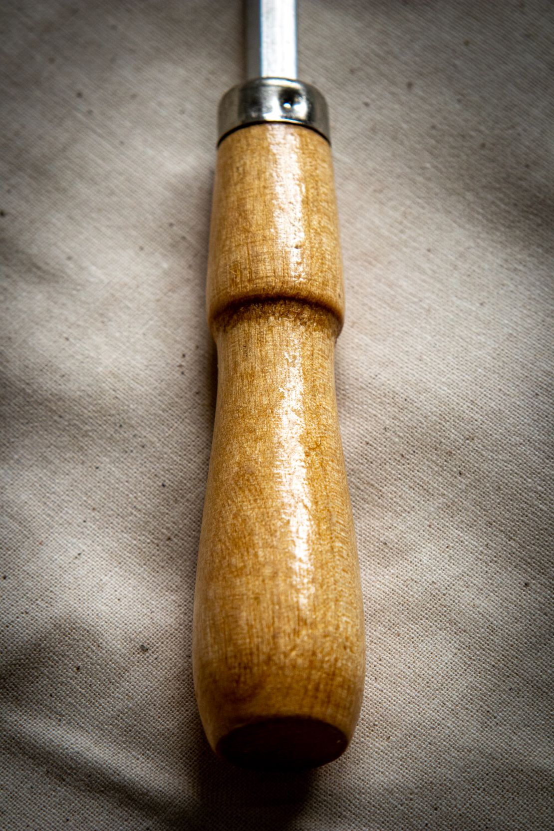 Tracing wheel with a wooden handle and silver metal wheel lying flat on a light grey surface, shown with full tool visible including smooth-grip handle tapering towards the wheel. Sold by RMIT Store.