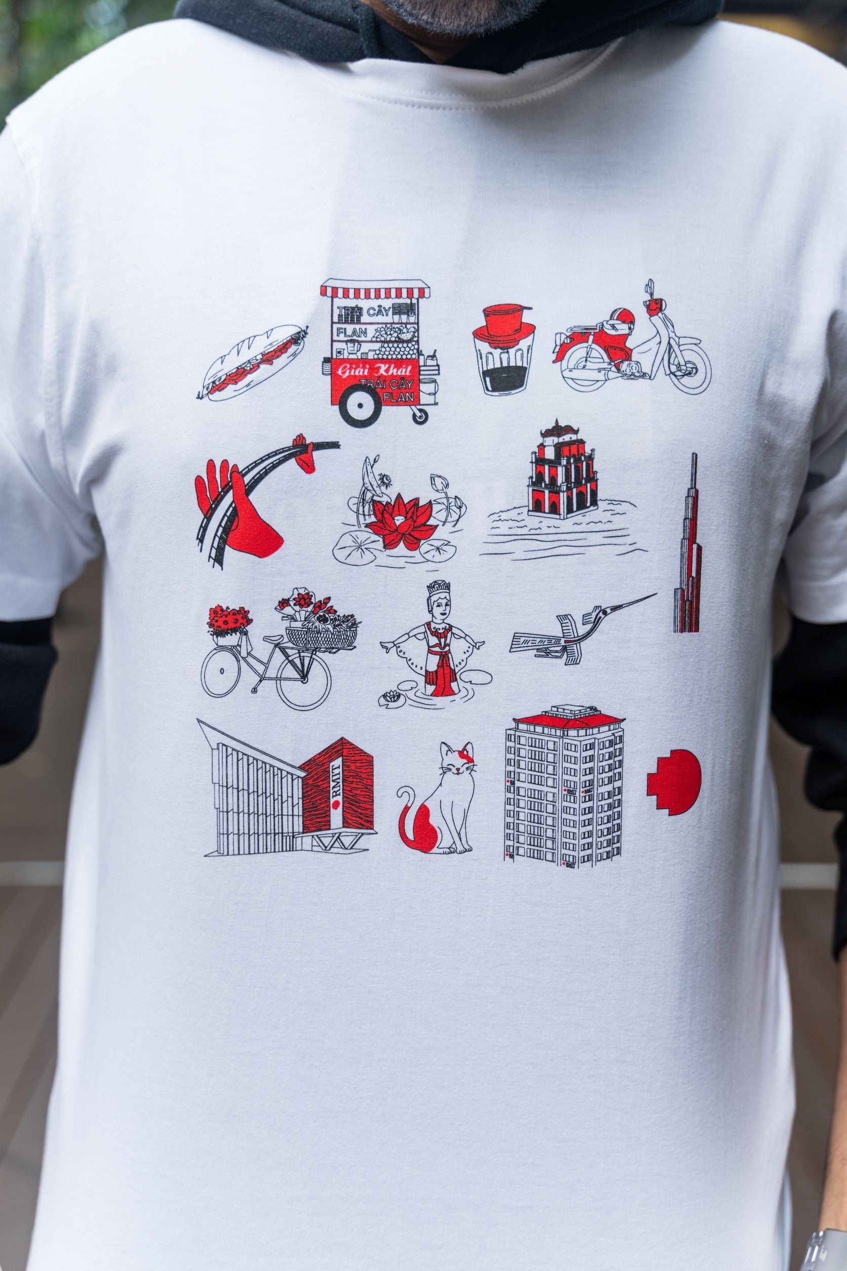 Close-up of the front design on the Vietnamese Icon Tee from RMIT Store, highlighting detailed red and black motifs of cultural icons like food carts and buildings.