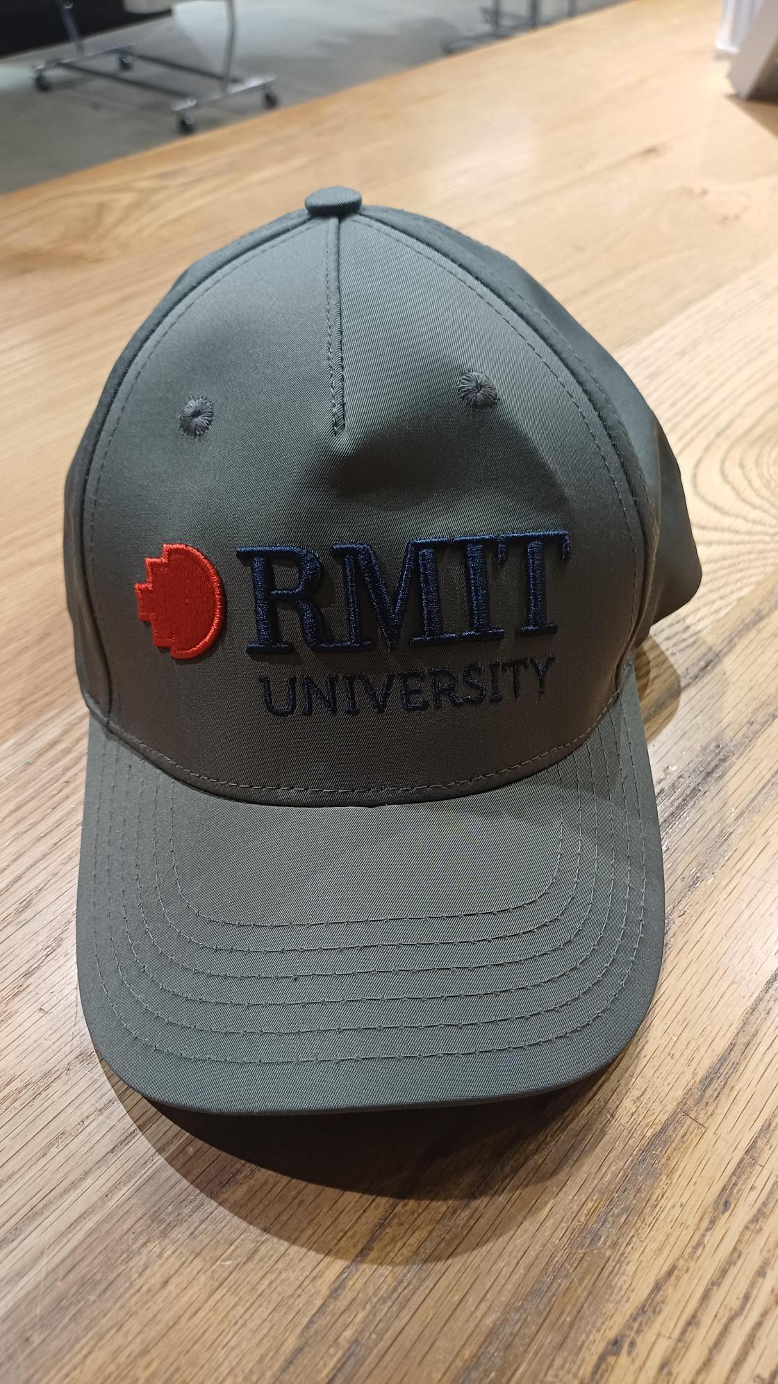Olive green cap featuring embroidered RMIT University branding on the front in navy and red, with a curved brim and stitched panel detailing.