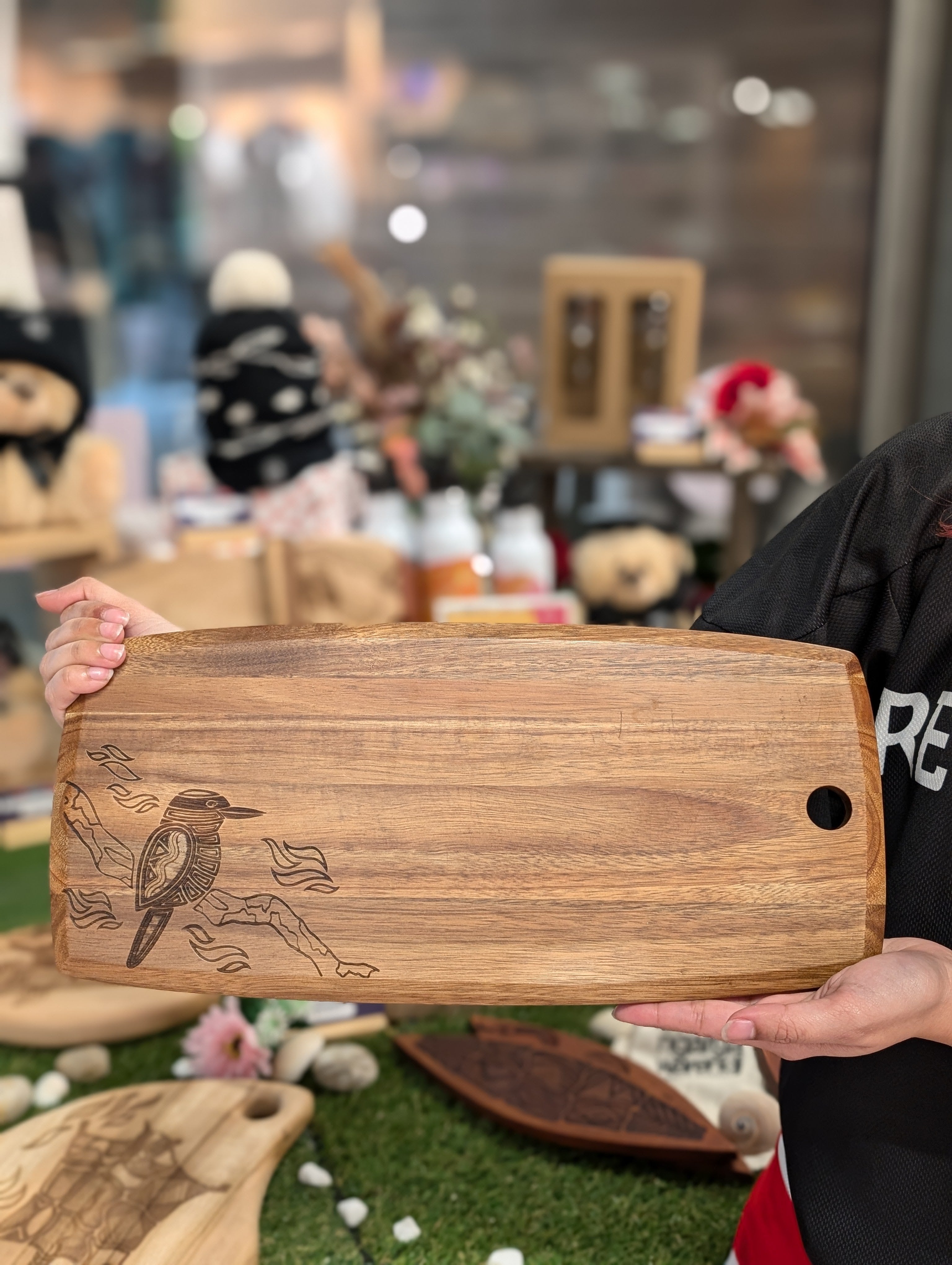 Ngarga Warendj Indigenous Australian designed Kookaburra engraved Acacia Wood Platter with RMIT Branding.  Top of the platter showing the Kookaburra engraved design shown while held by model.
