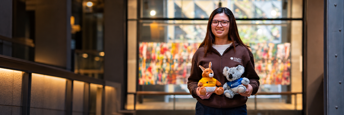 Model holding Kangaroo and Koala Plushies on campus.