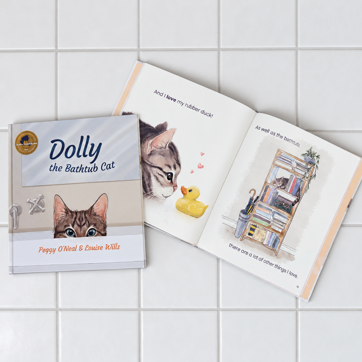 Flat lay of Dolly the Bathtub Cat showing the cover beside illustrated pages featuring Dolly, a rubber duck and a bookcase.