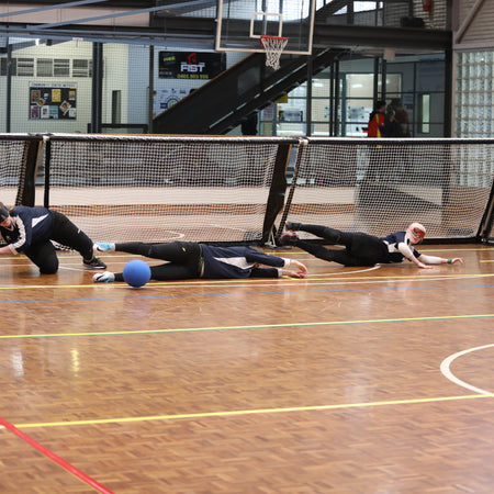 Goalball competitors diving for a ball during a match
