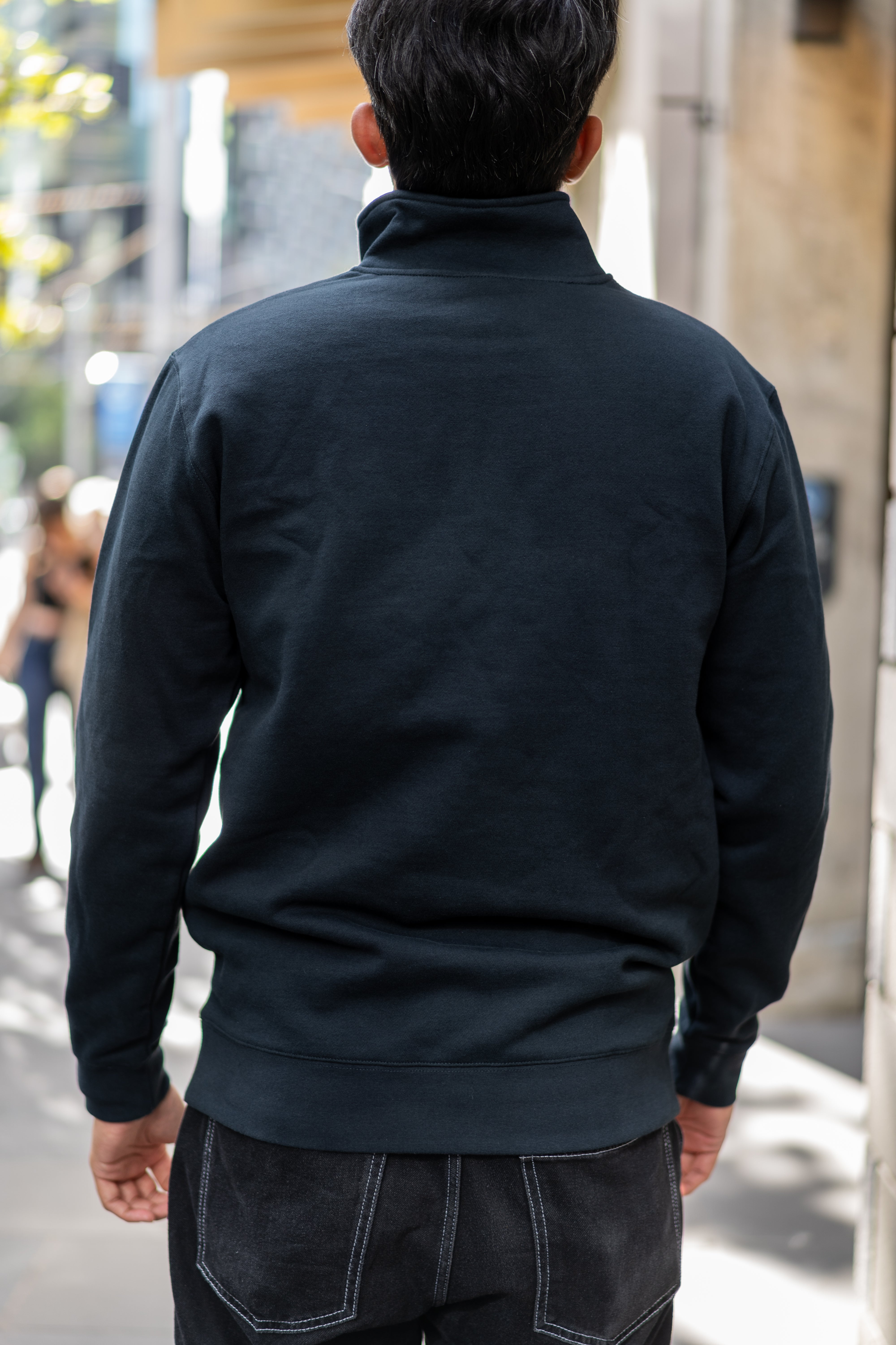 Back view of student wearing RMIT Essential half zip jumper in navy on campus.